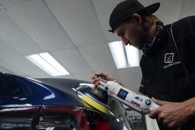 A man is polishing a car with a machine.