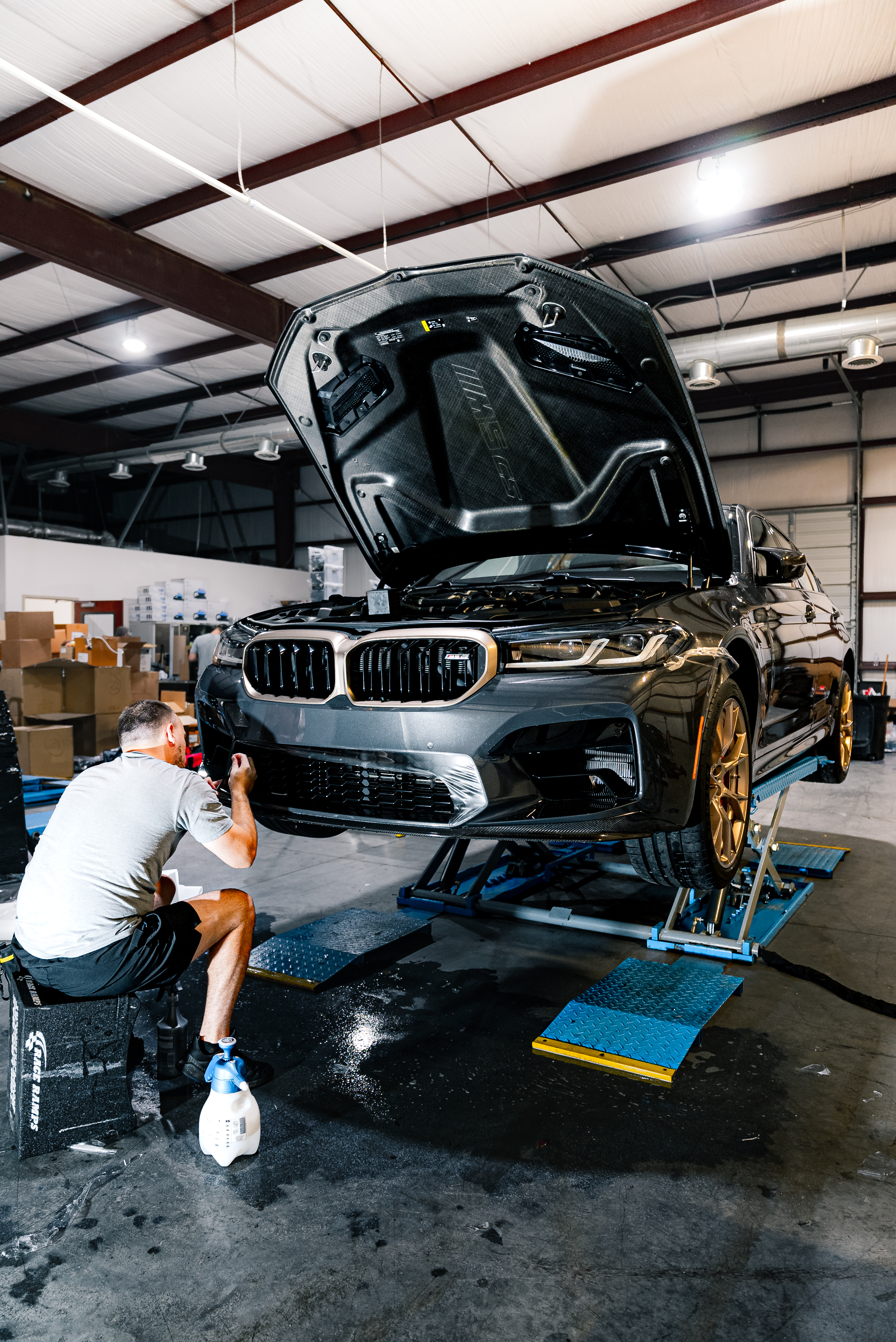 A man is covering the hood of a gmc truck with plastic wrap.