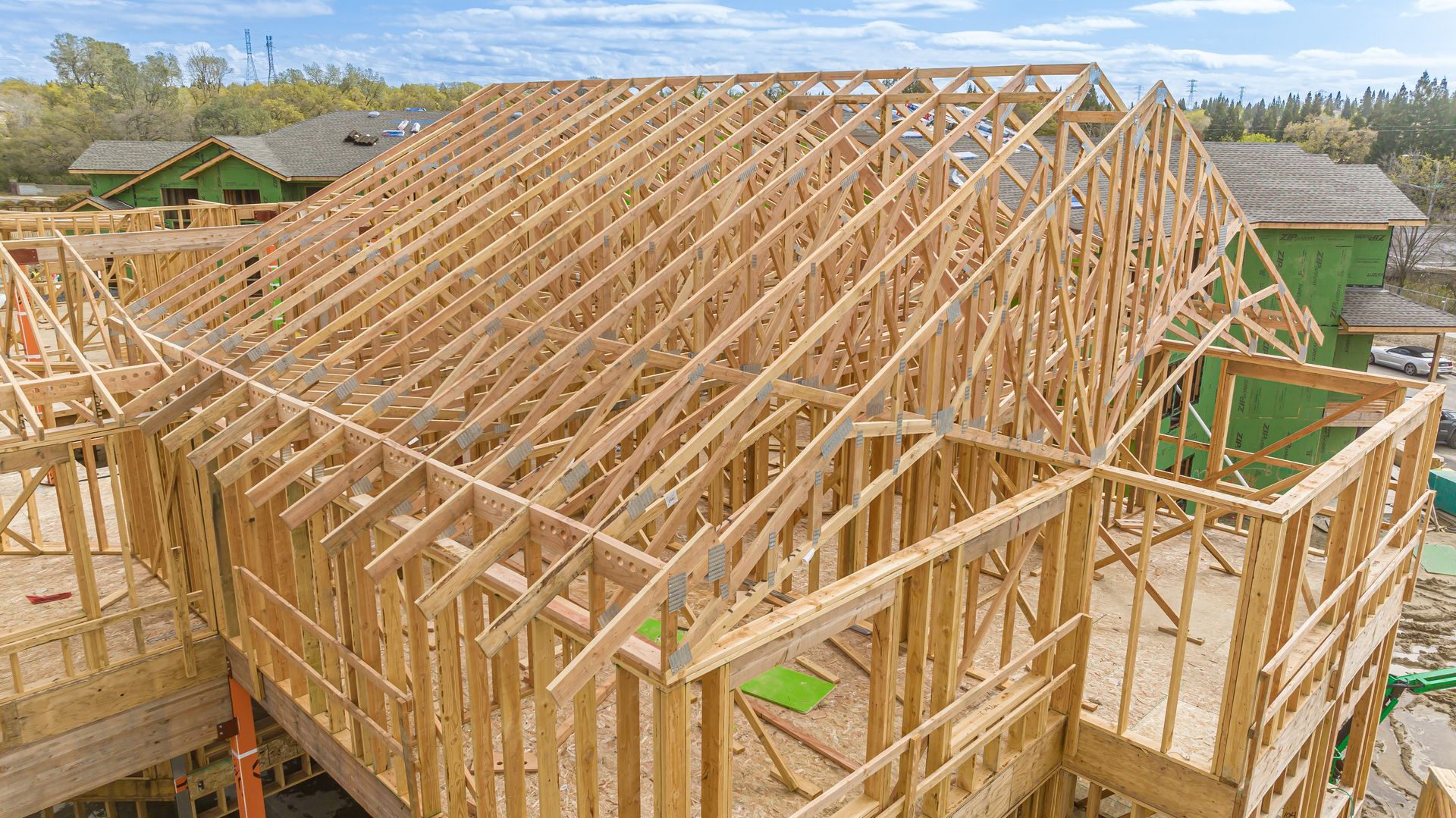 Wooden house frame under construction with exposed roof trusses and walls