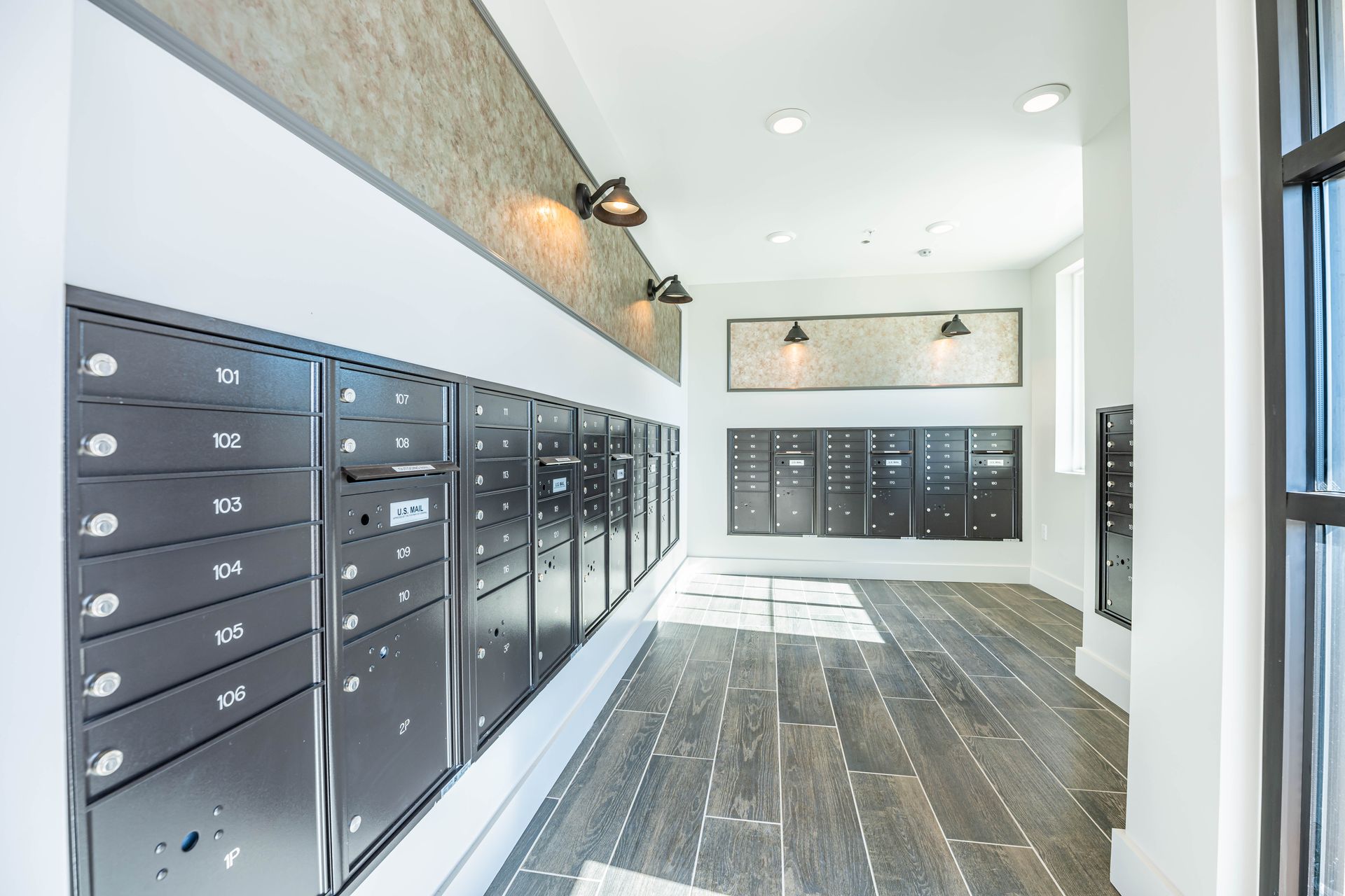 Modern apartment lobby with black mailboxes and wood-look tile floor