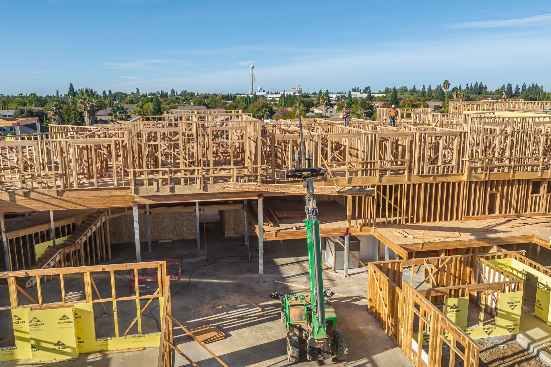 Construction site with wooden framing and a green crane under a clear sky