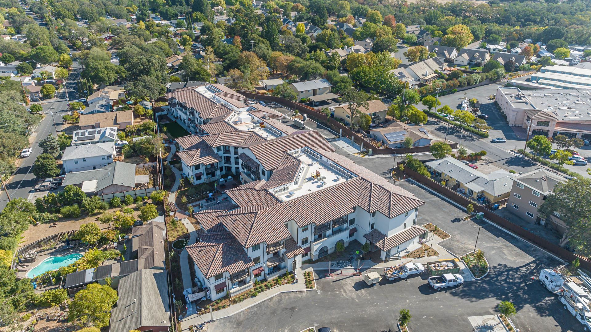 Aerial view of a large tiled-roof building complex surrounded by trees and streets in a residential area