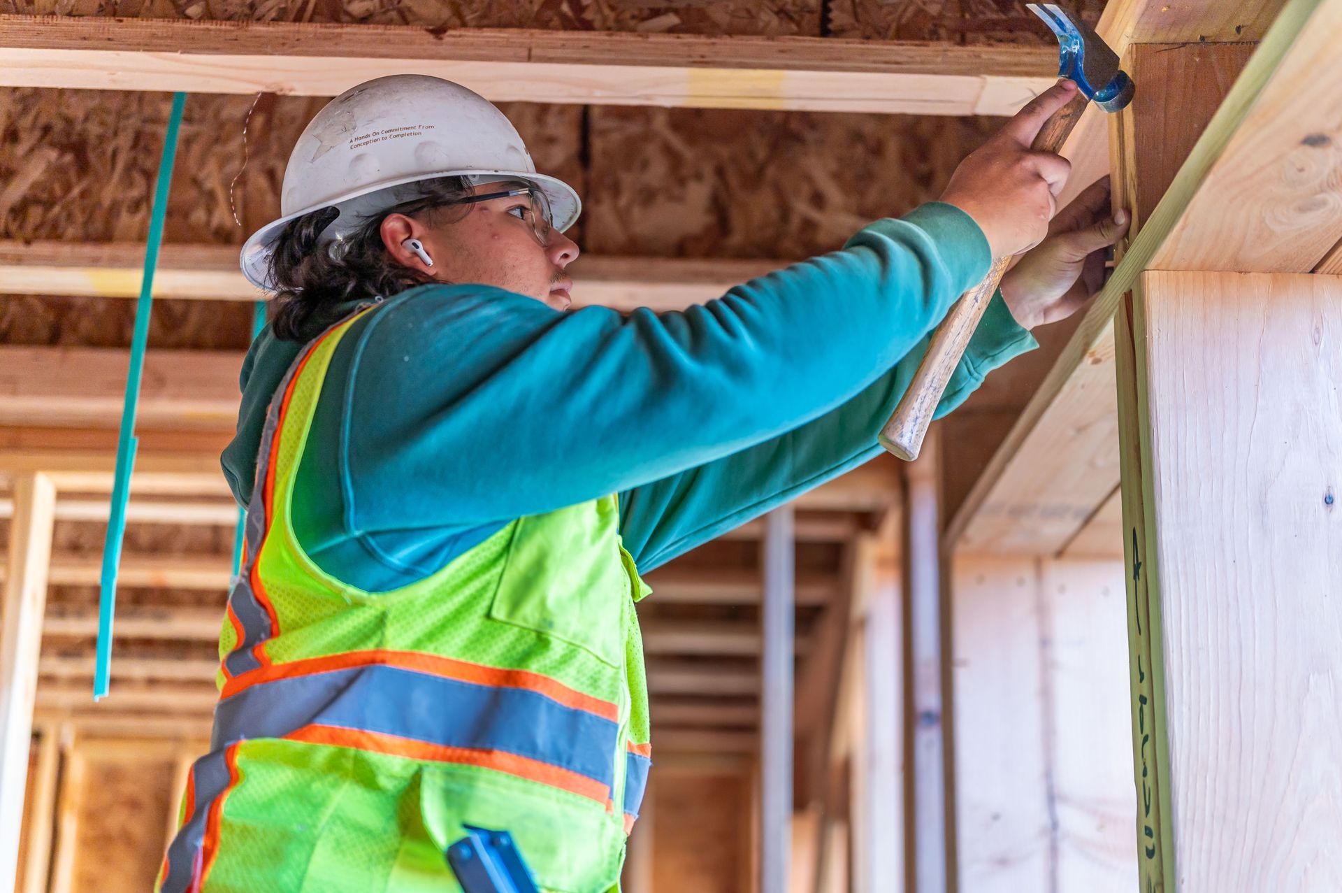 Construction worker nailing wooden beams in a framed building interior