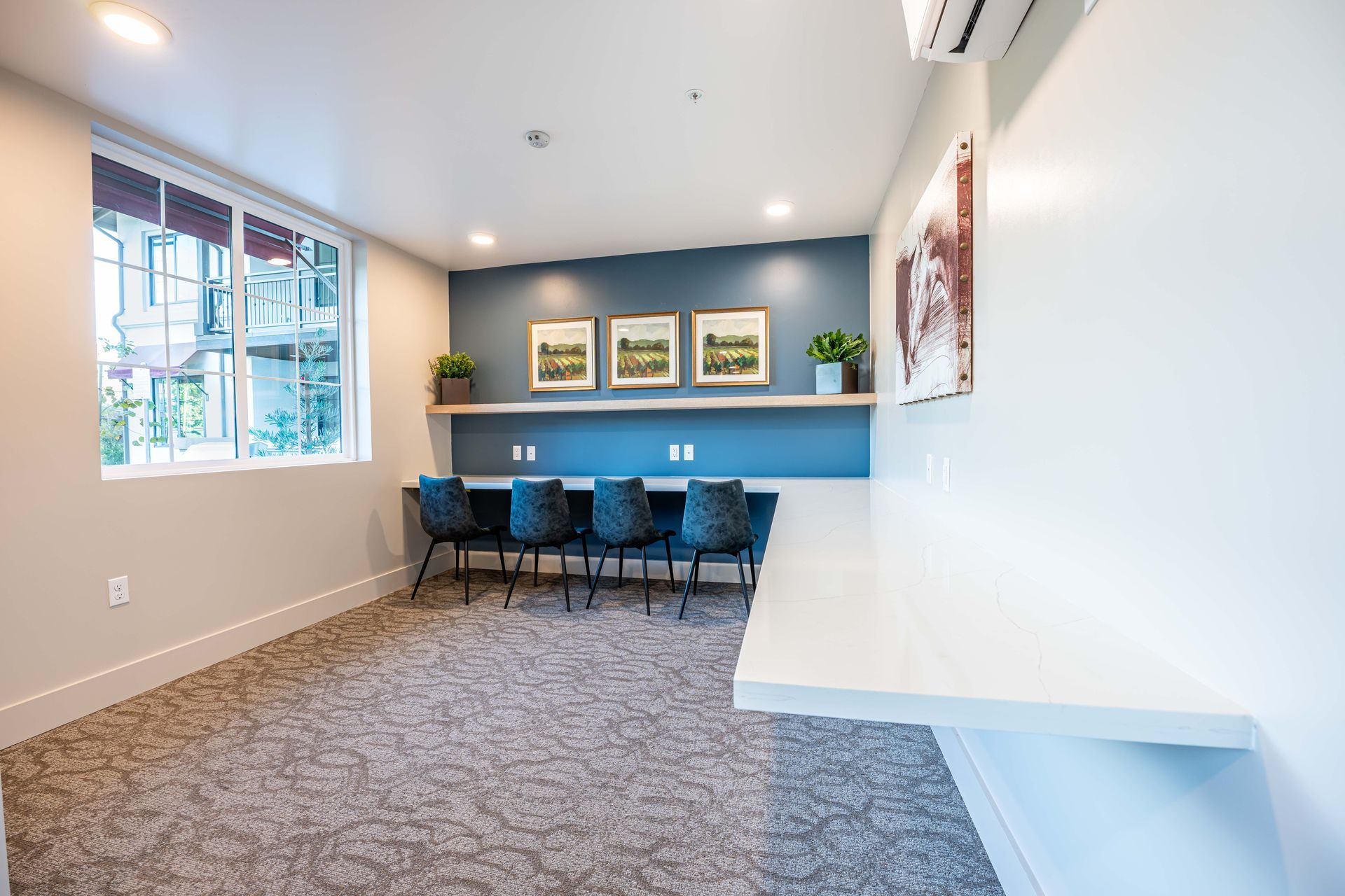 Modern waiting room with blue accent wall, desk, chairs, and large windows