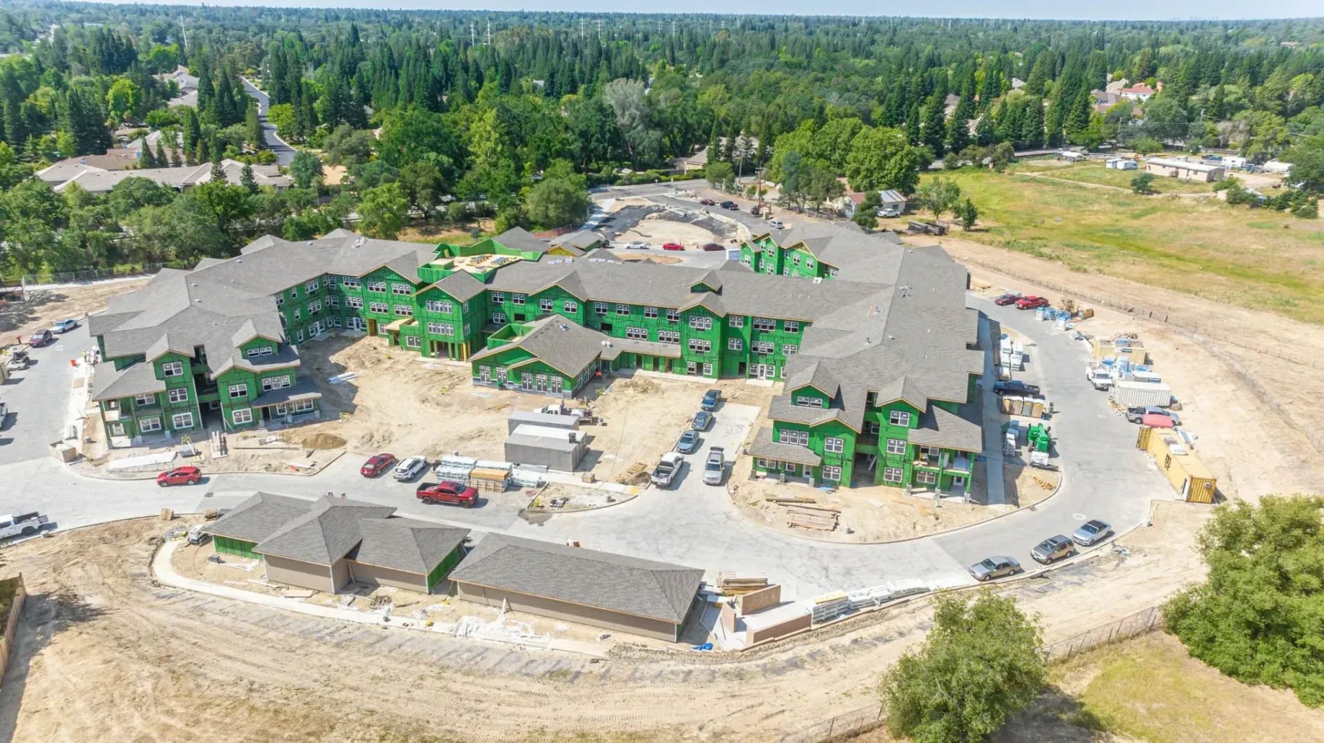Aerial view of a large resort-style building complex surrounded by trees and parking areas.