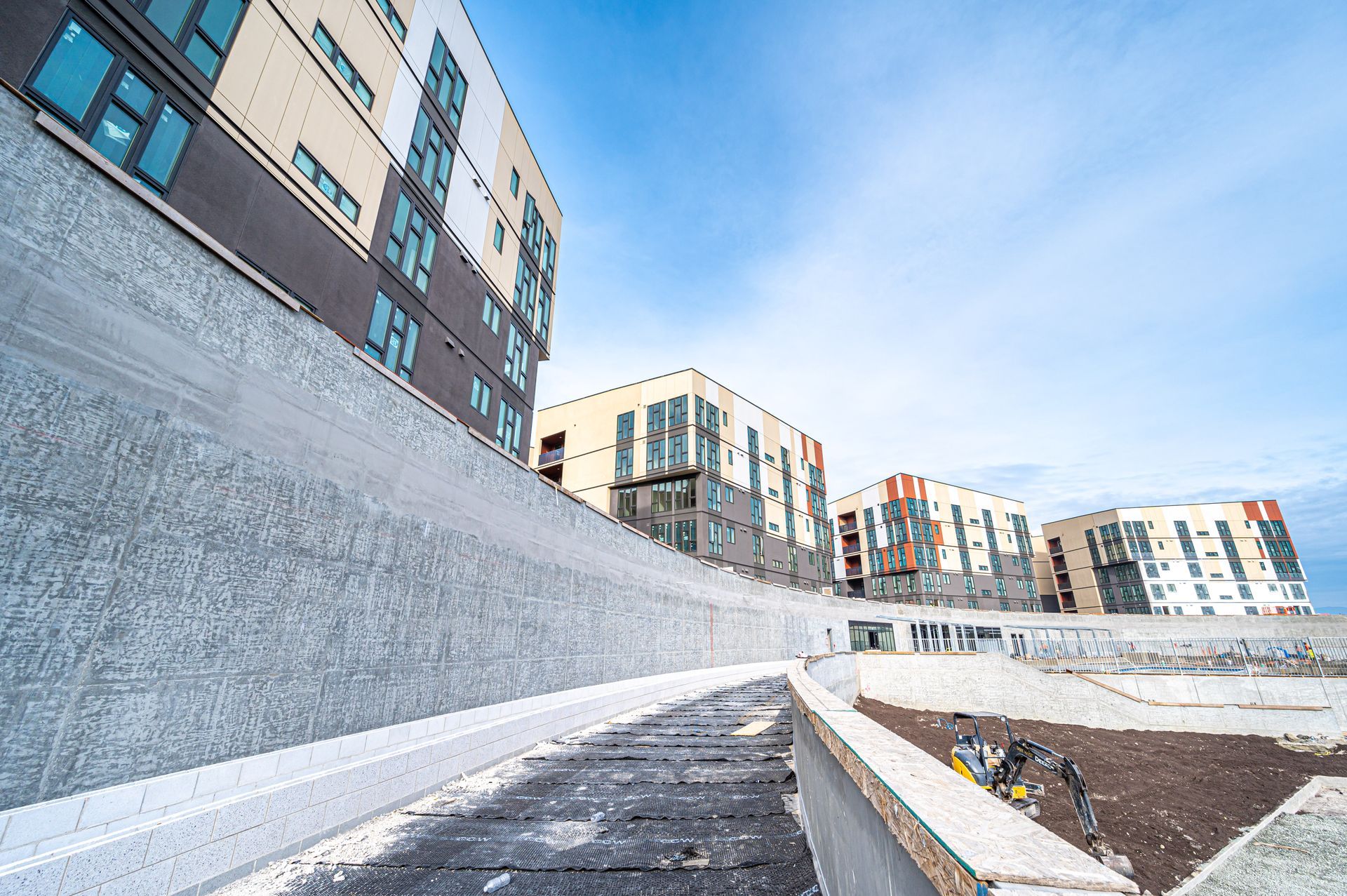 Modern apartment buildings beside a snow-covered walkway under a blue sky