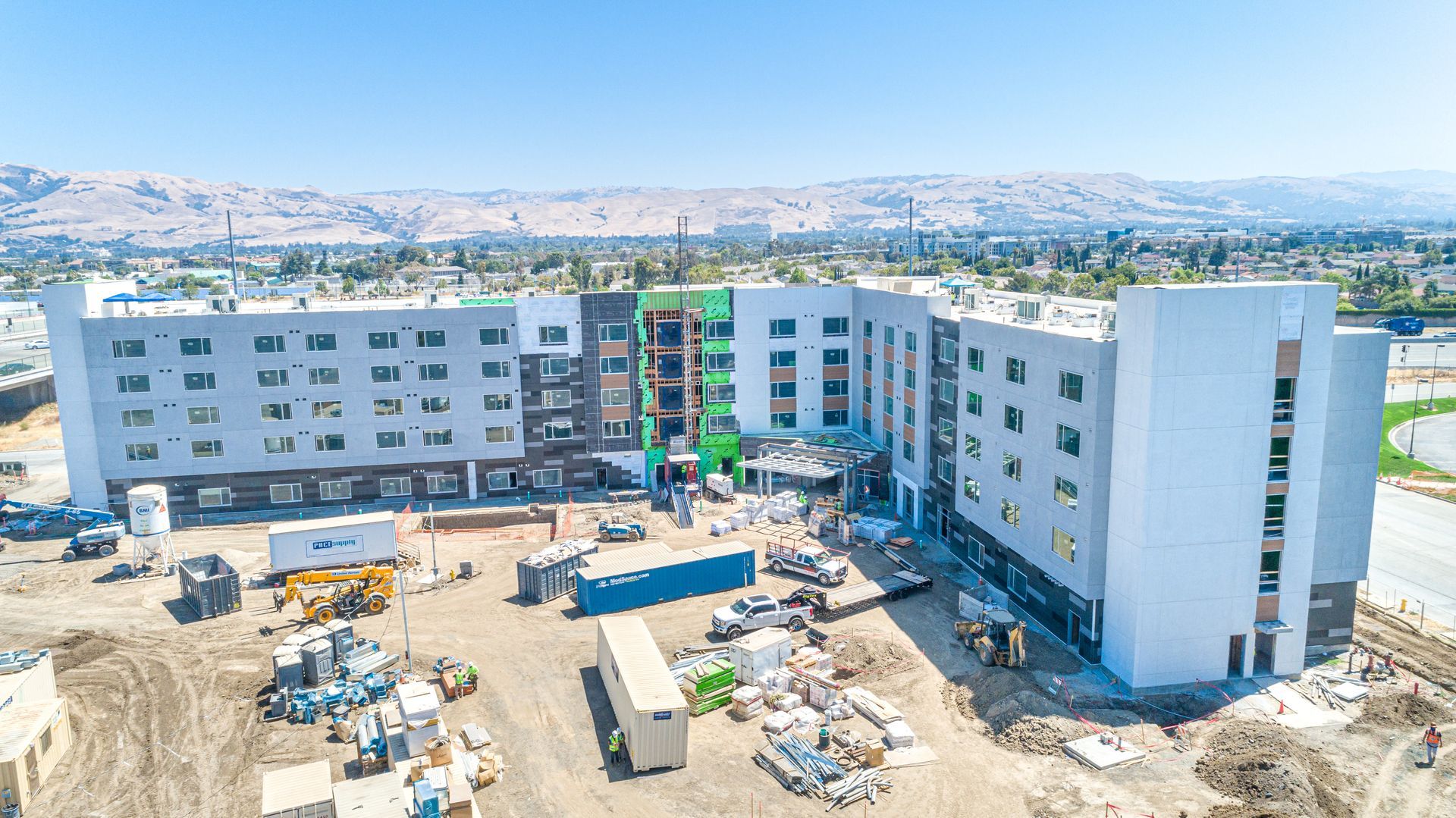 Aerial view of a large apartment complex under construction in a dusty urban area