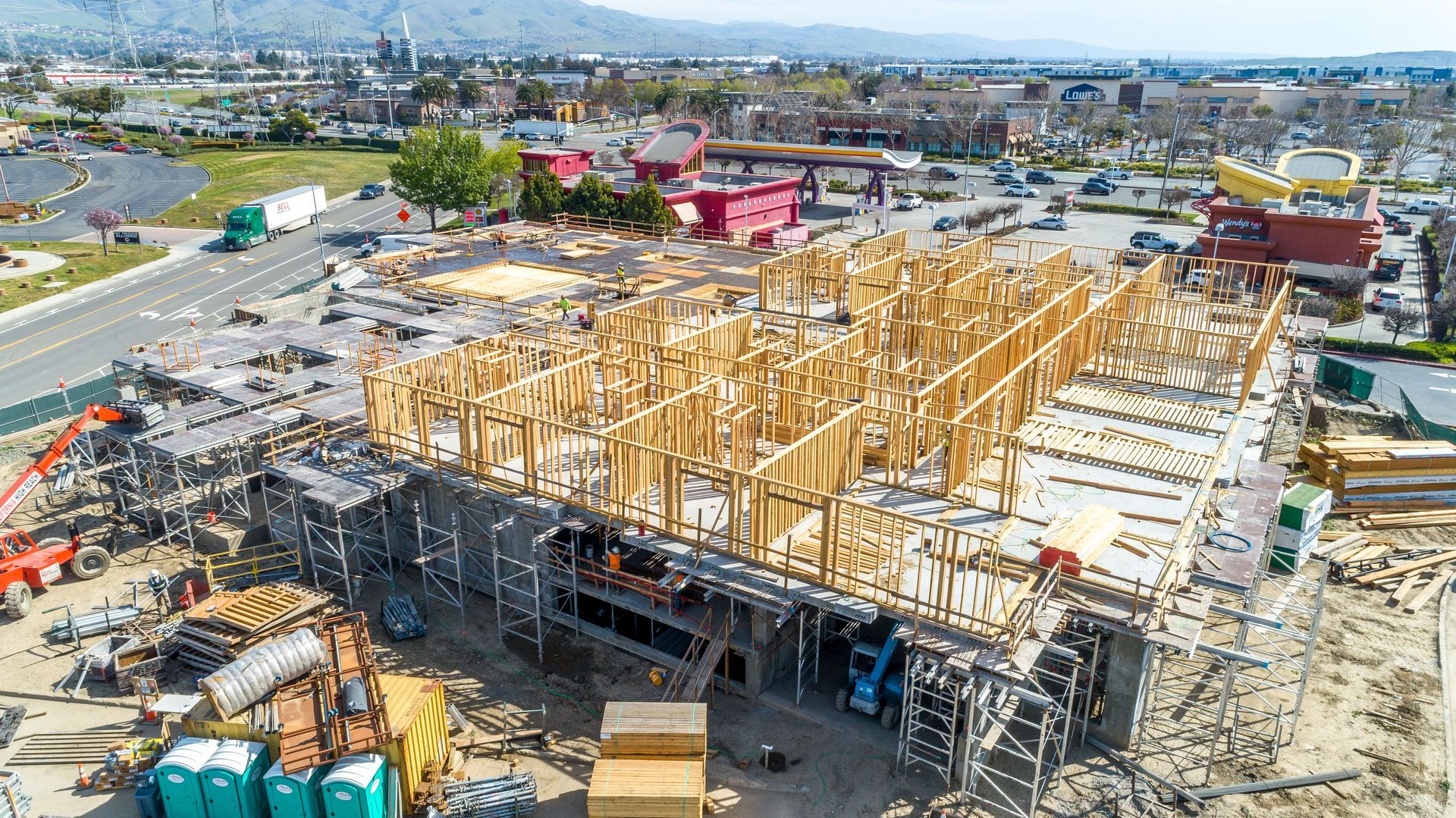 Large construction site with wooden framing and cranes in an urban area