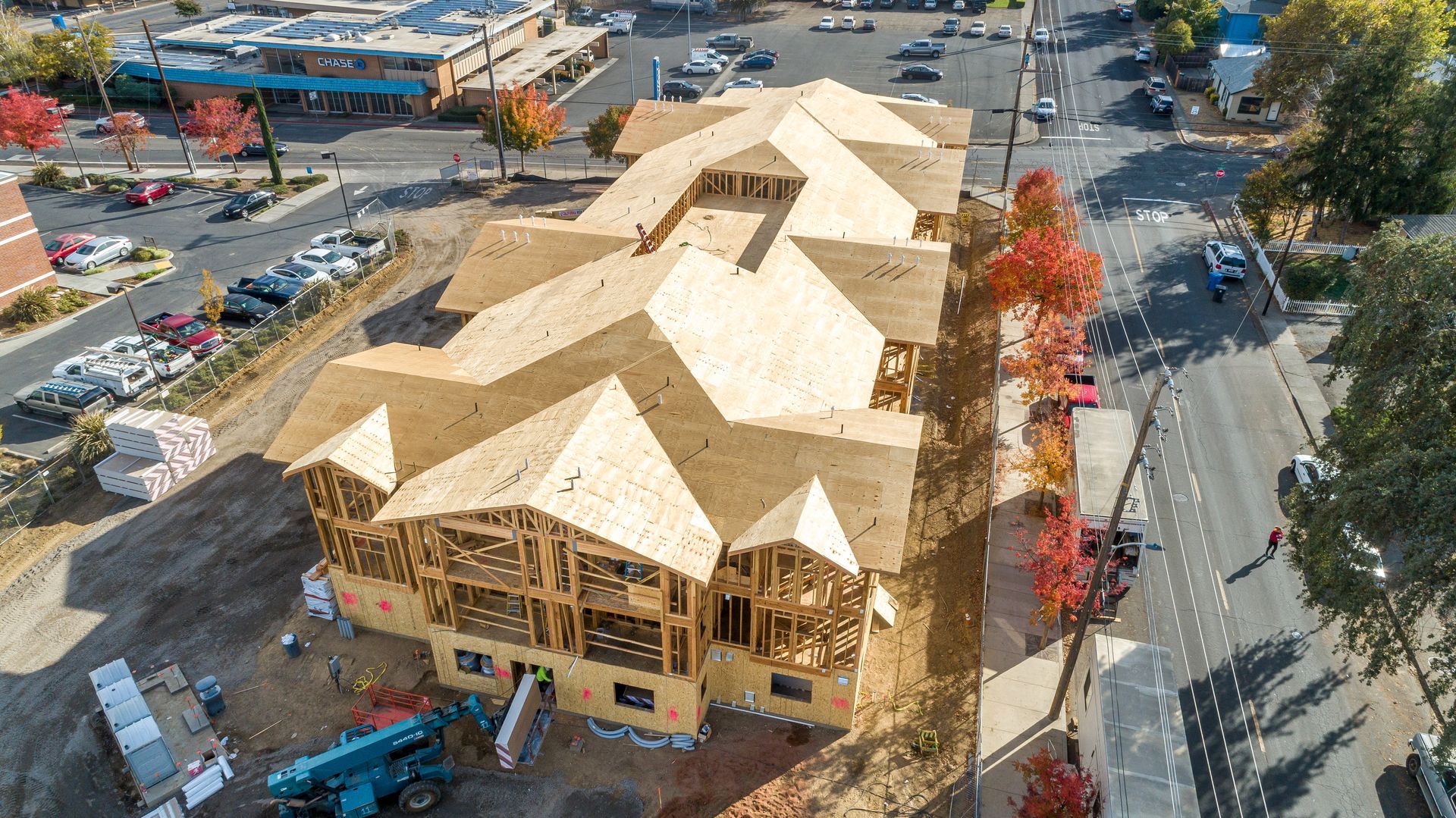 Aerial view of a large house under construction with a wooden roof frame and surrounding equipment