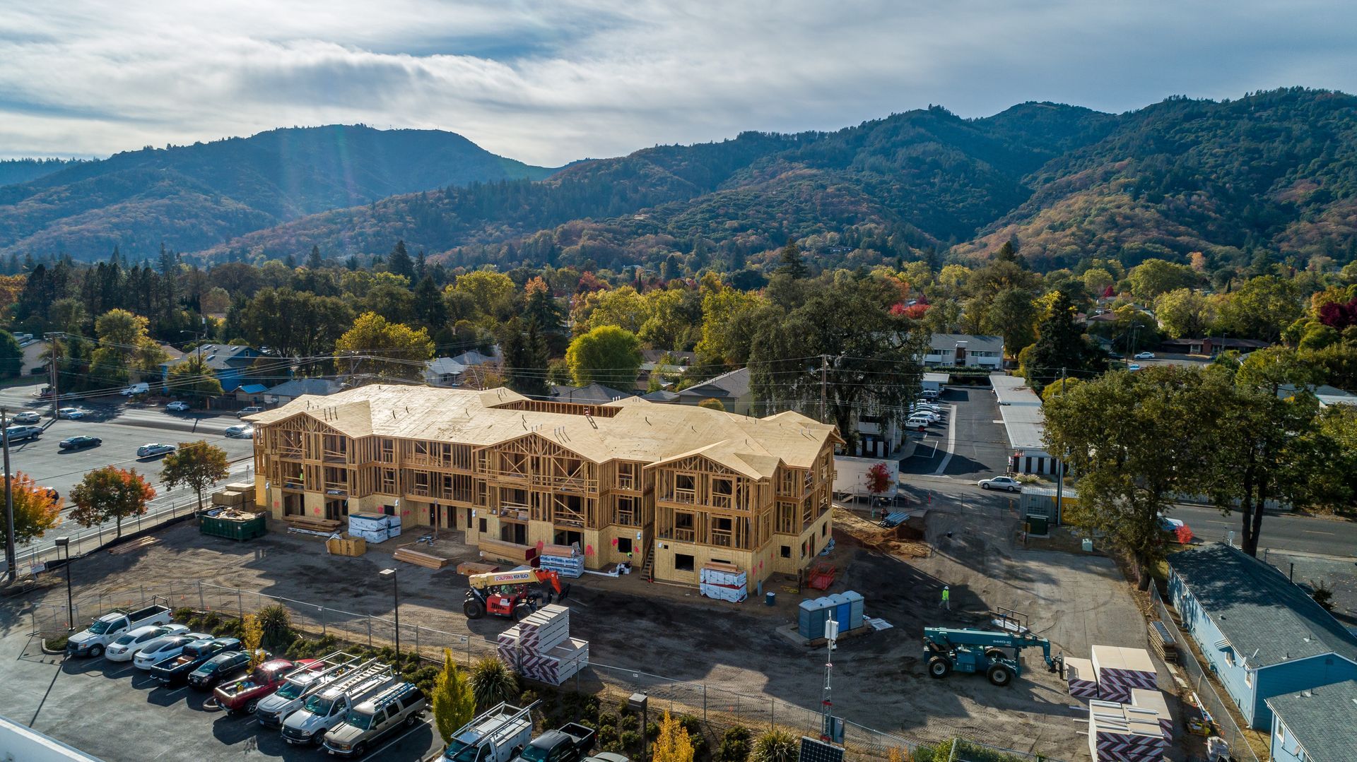 Aerial view of a building under construction with mountains and trees in the background