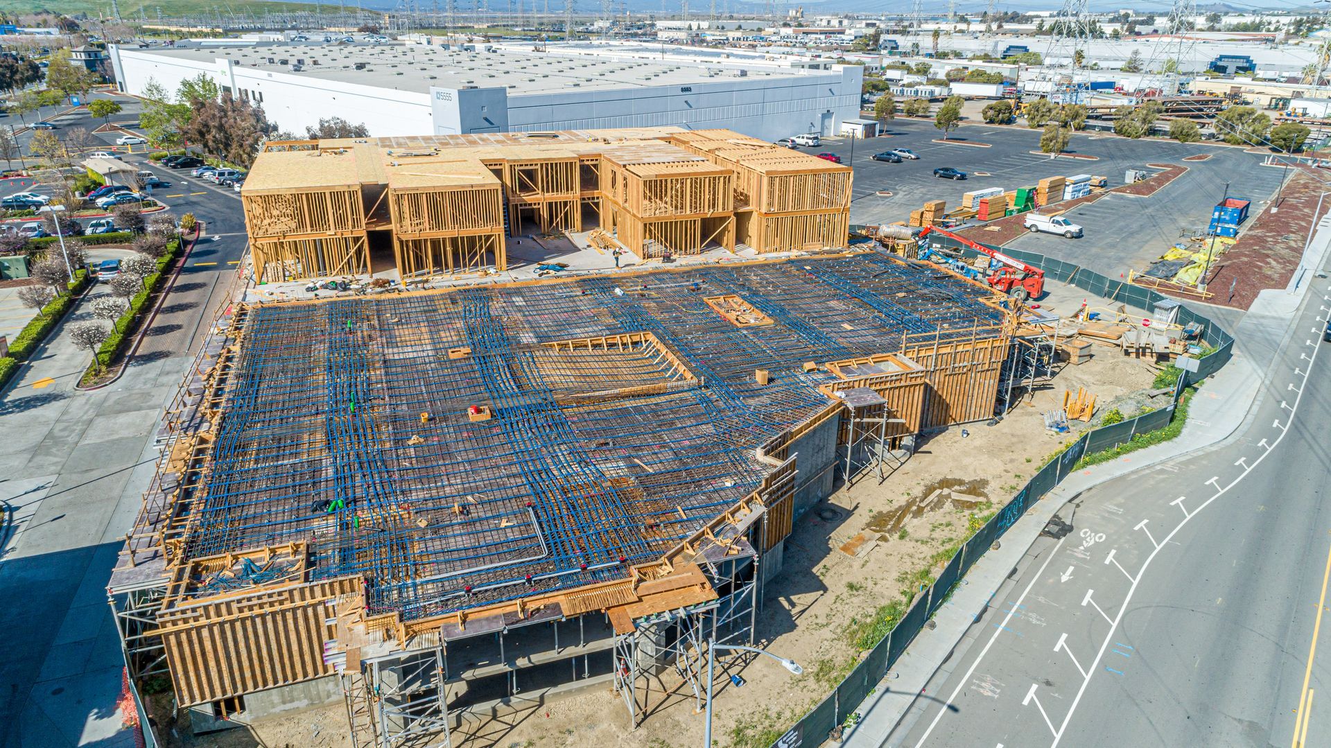 Aerial view of a large wooden building under construction beside a road in an industrial area