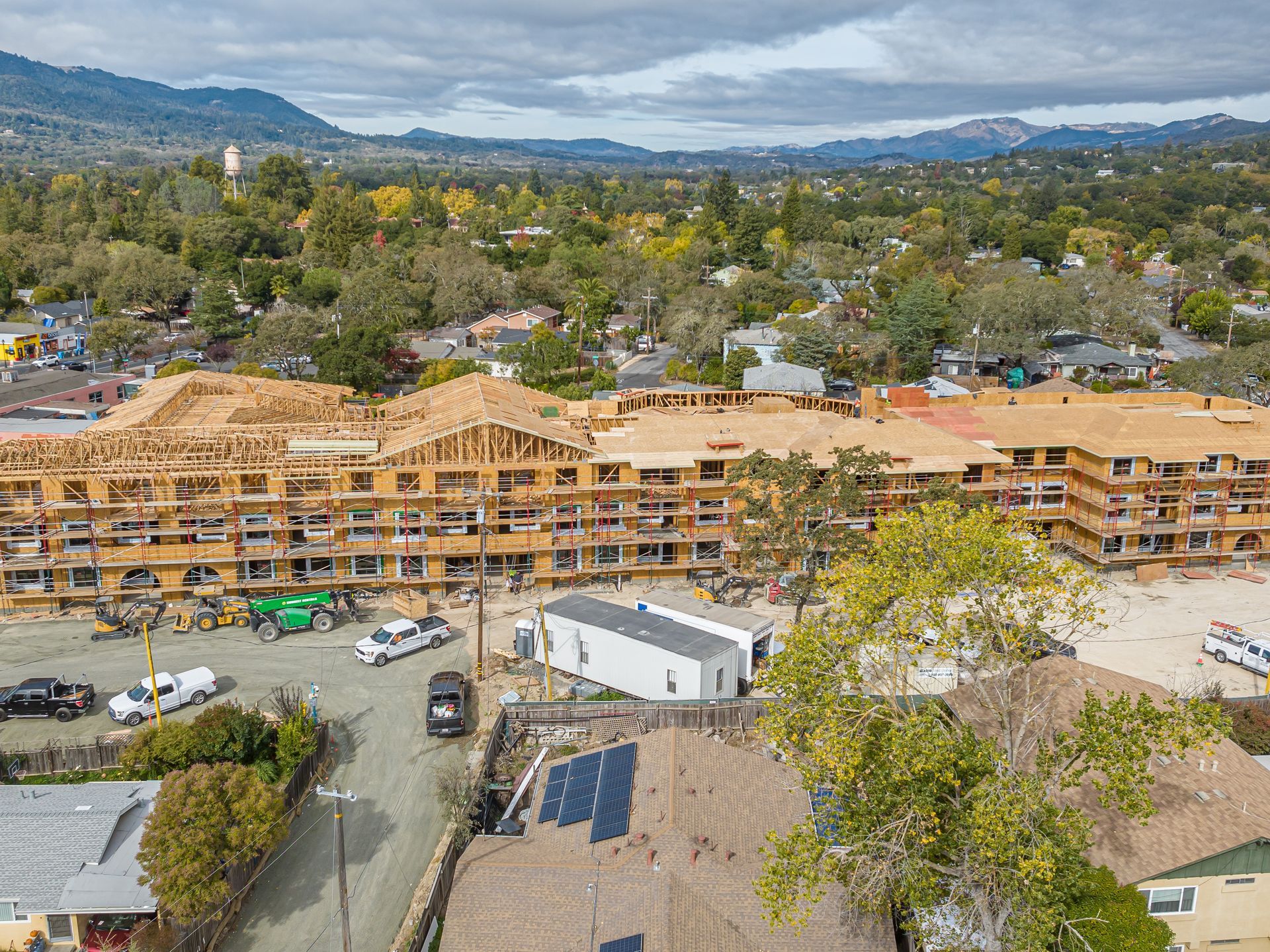 Aerial view of a large wood-framed apartment complex under construction in a suburban area