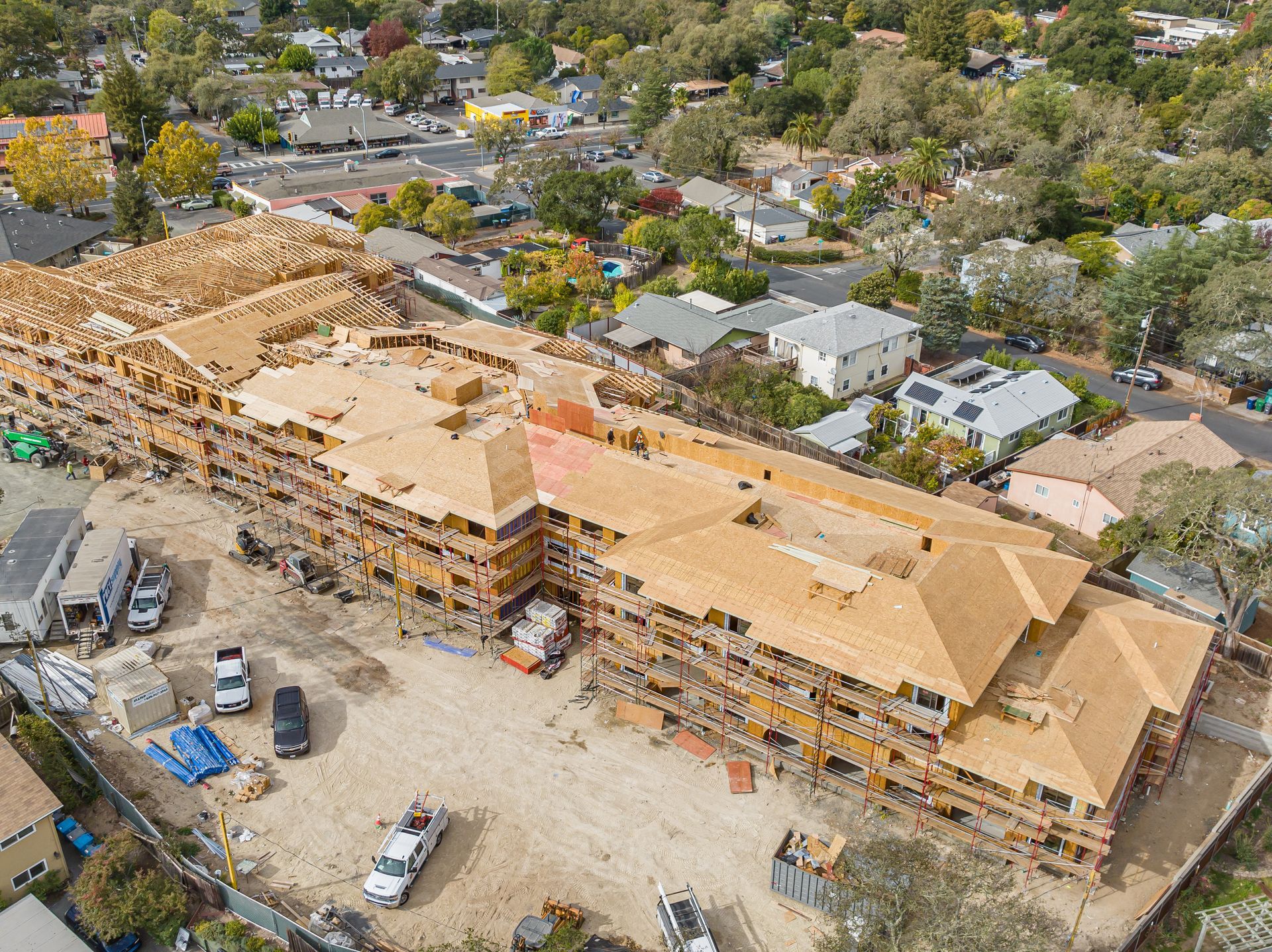 Aerial view of a wildfire-damaged apartment complex with burned roofs and scattered debris in a neighborhood