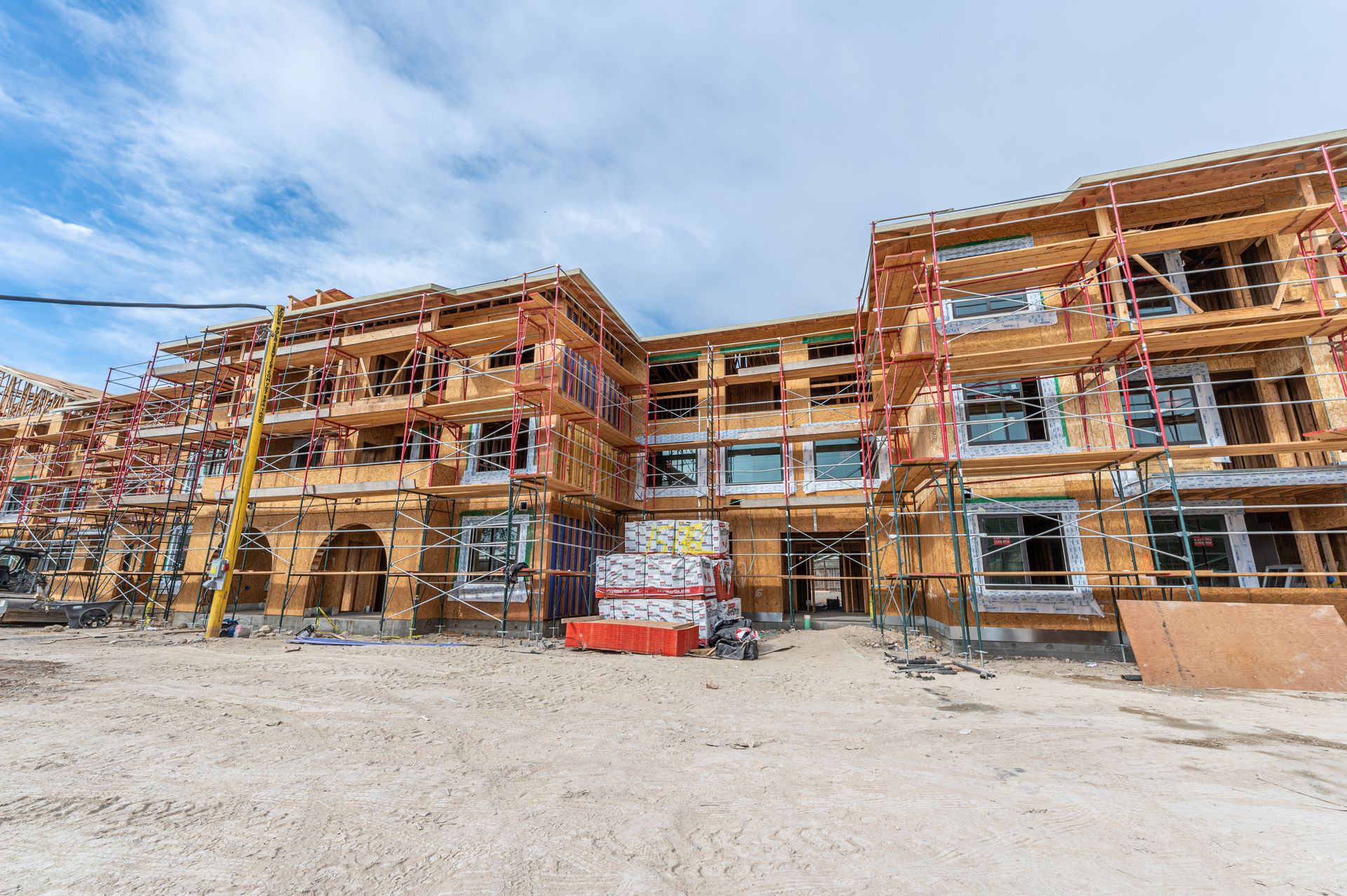 Partially built apartment complex with scaffolding under a clear blue sky