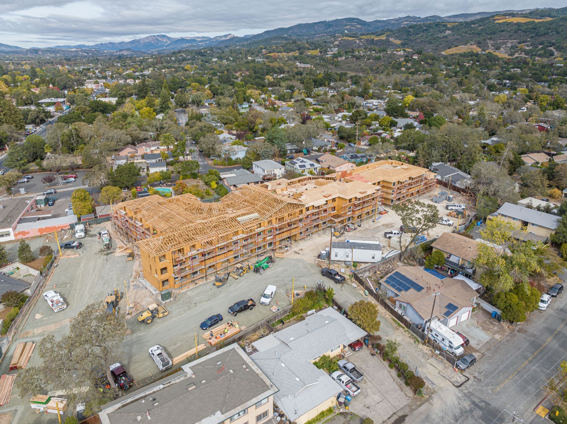 Aerial view of a residential neighborhood with a large wooden building under construction.