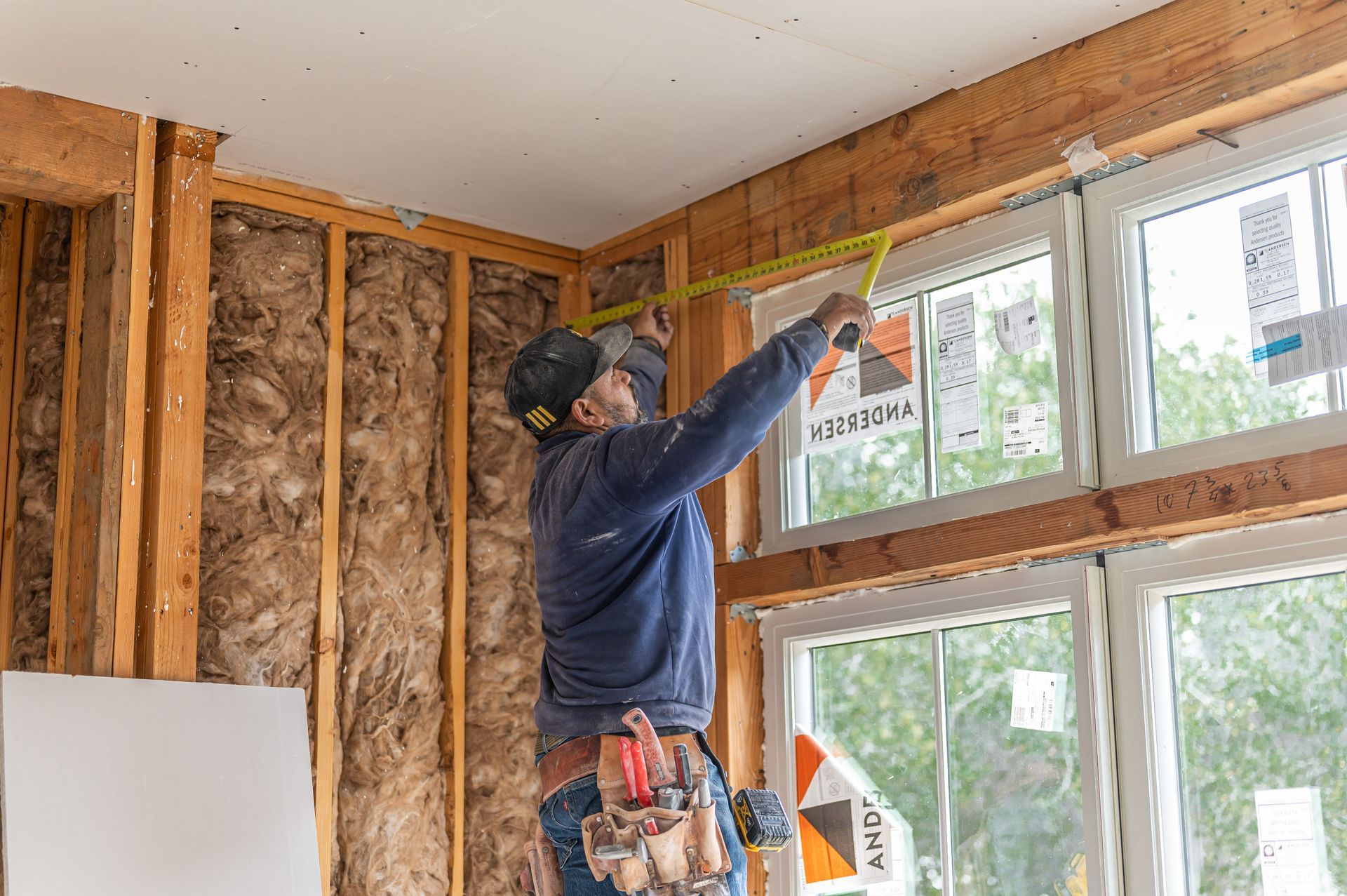 Worker measuring a window frame inside a house under renovation
