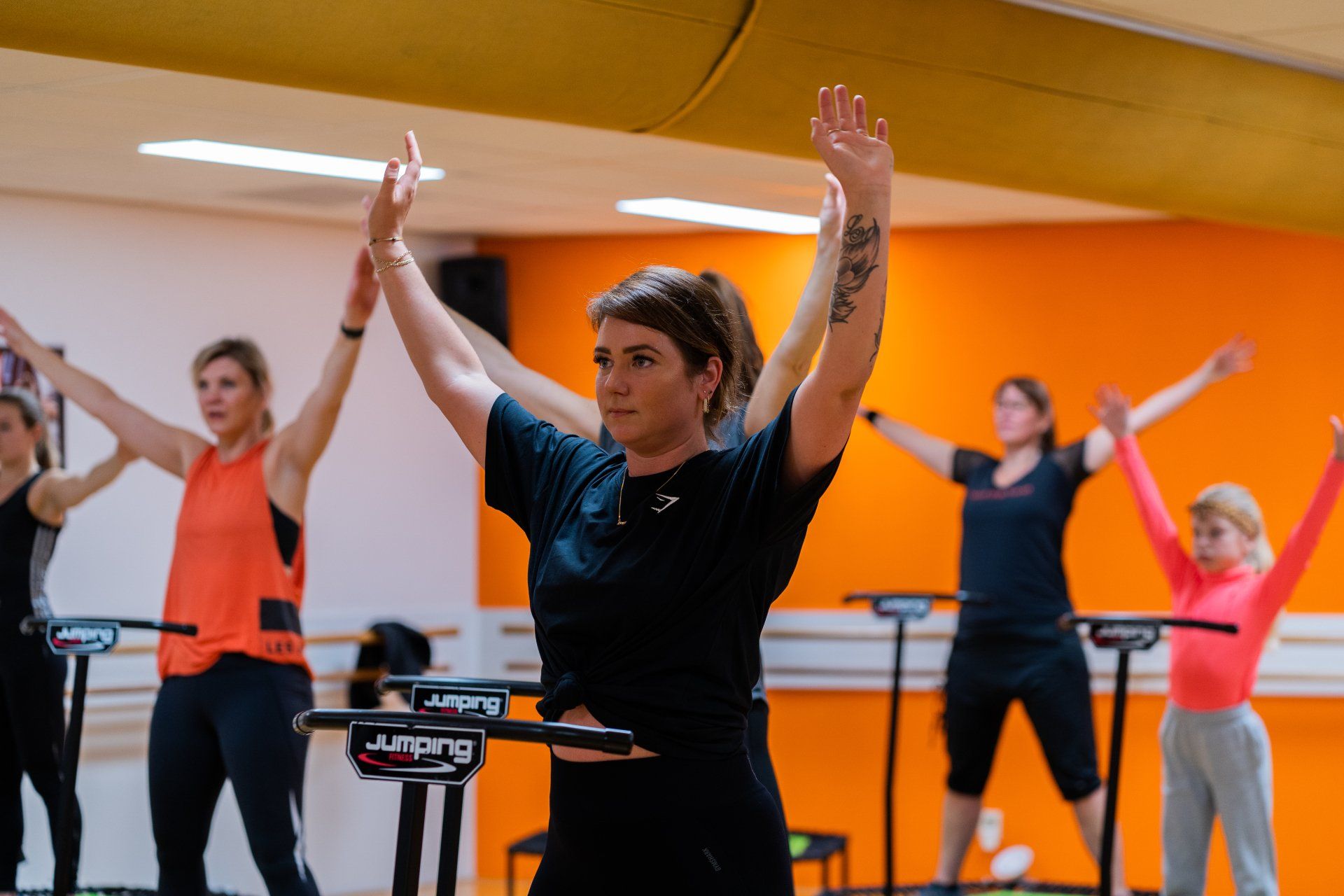 Een groep vrouwen doet oefeningen op een trampoline in een sportschool.