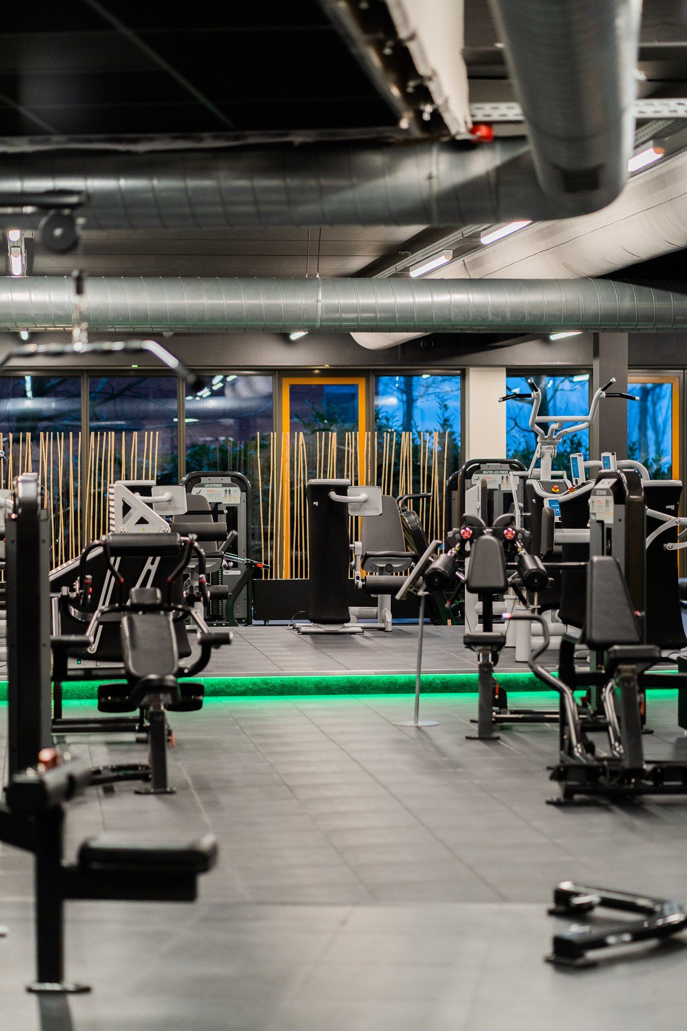Een sportschool vol met veel fitnessapparatuur en groen licht.