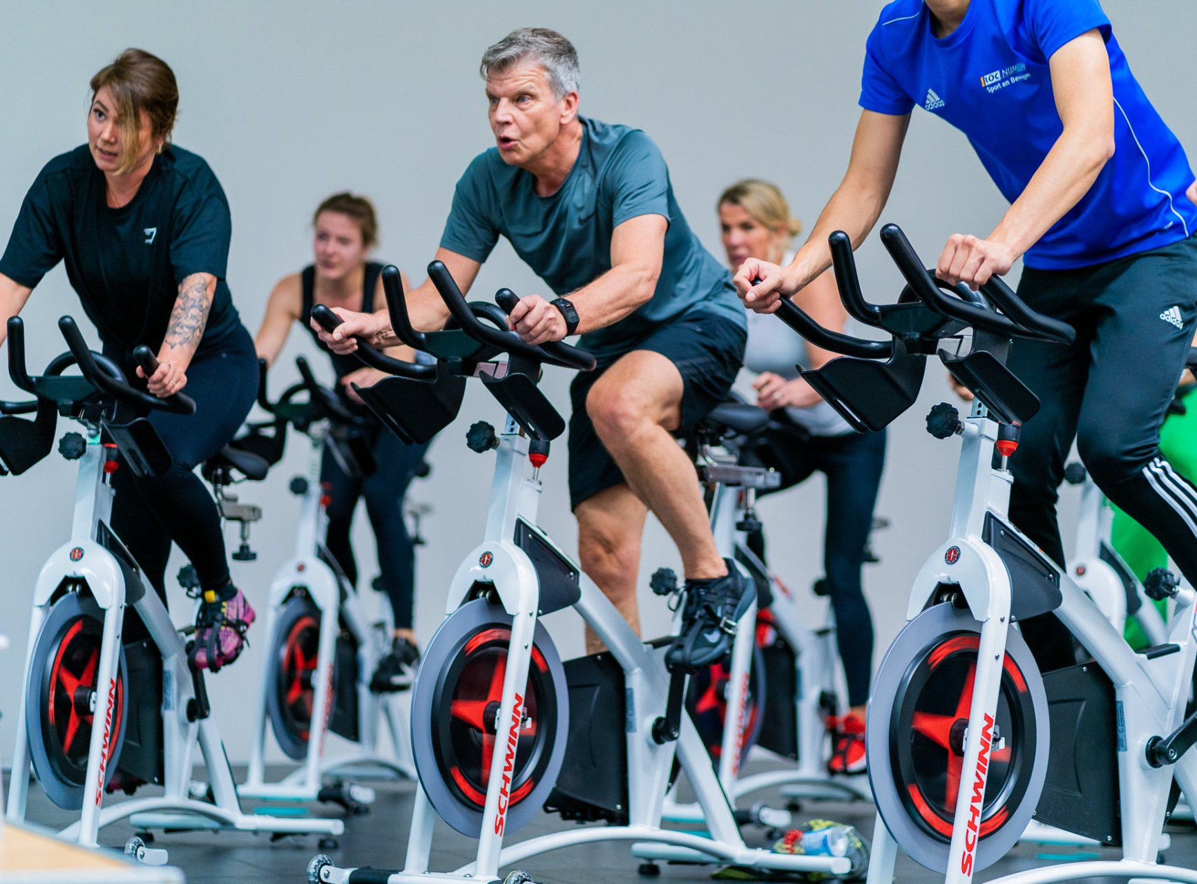 Een groep mensen rijdt op hometrainers in een sportschool.