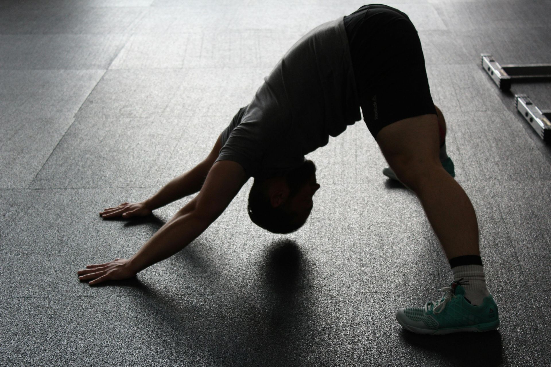 Een man doet een yogahouding op de vloer in een sportschool.
