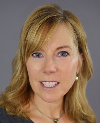 A woman wearing a necklace and earrings is smiling for the camera.