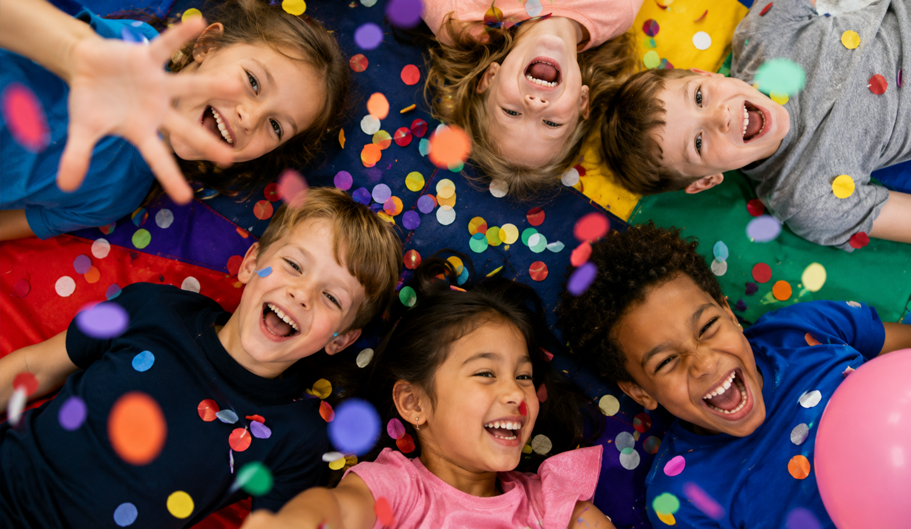 Children lying in a colorful confetti pile, smiling and laughing overhead
