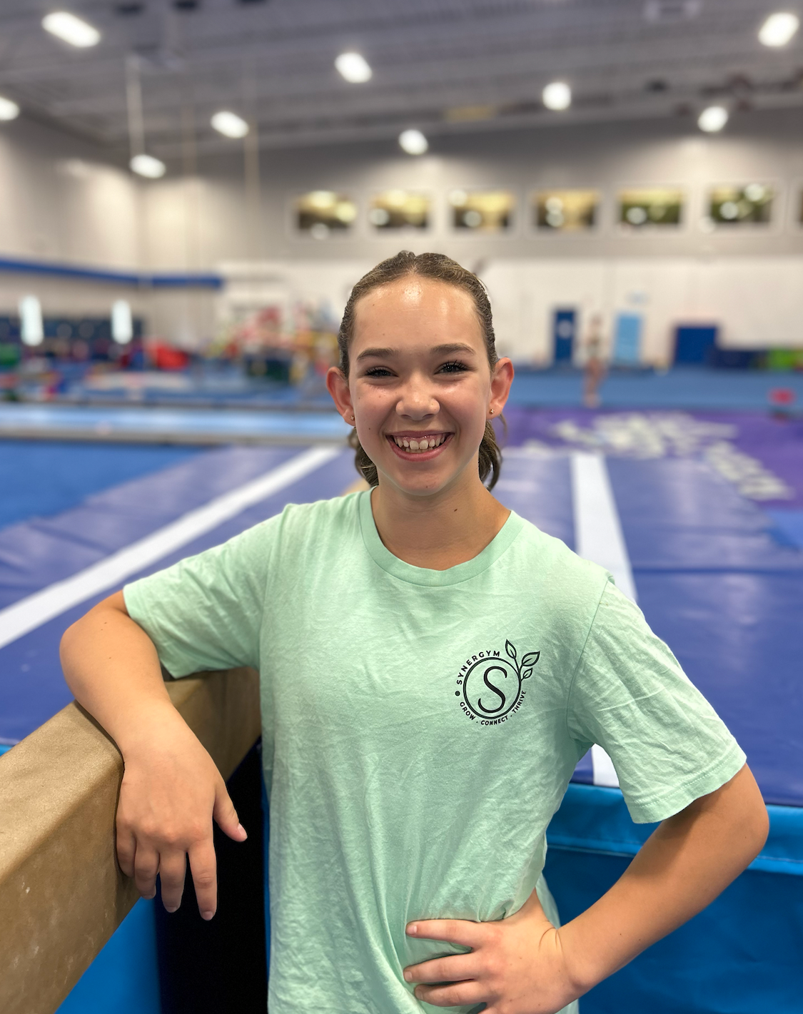 Smiling athlete in a mint T-shirt leaning on a pool deck at an indoor swimming facility