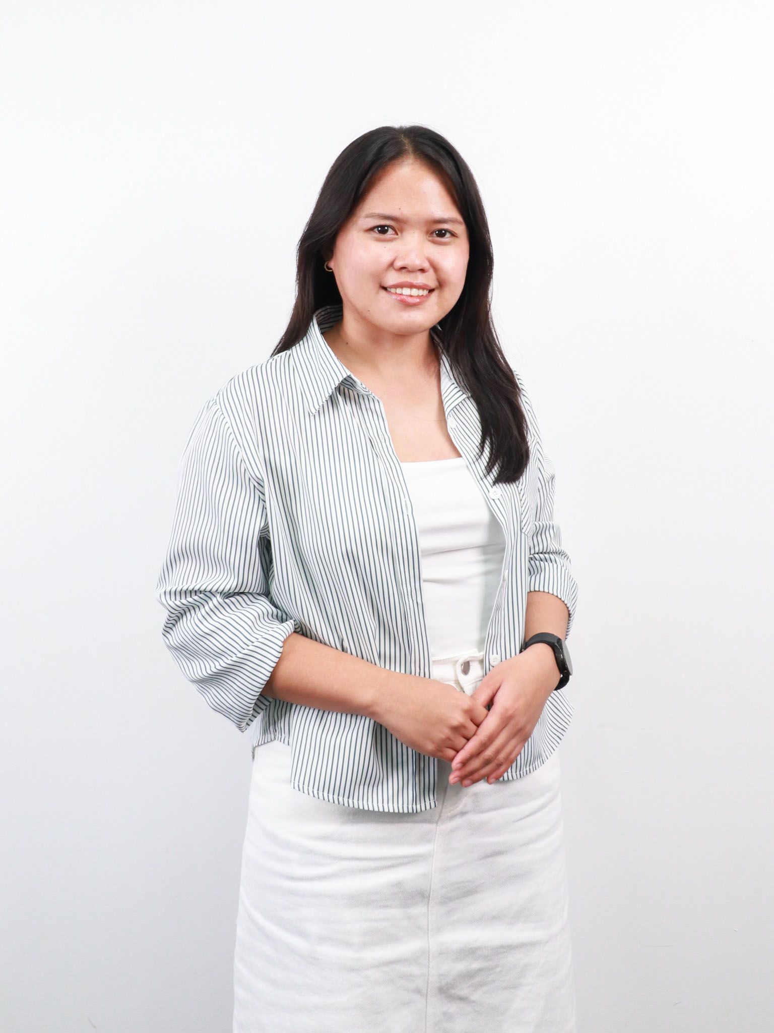 Portrait of a smiling person with long dark hair, wearing a yellow sweater over a white collared shirt.