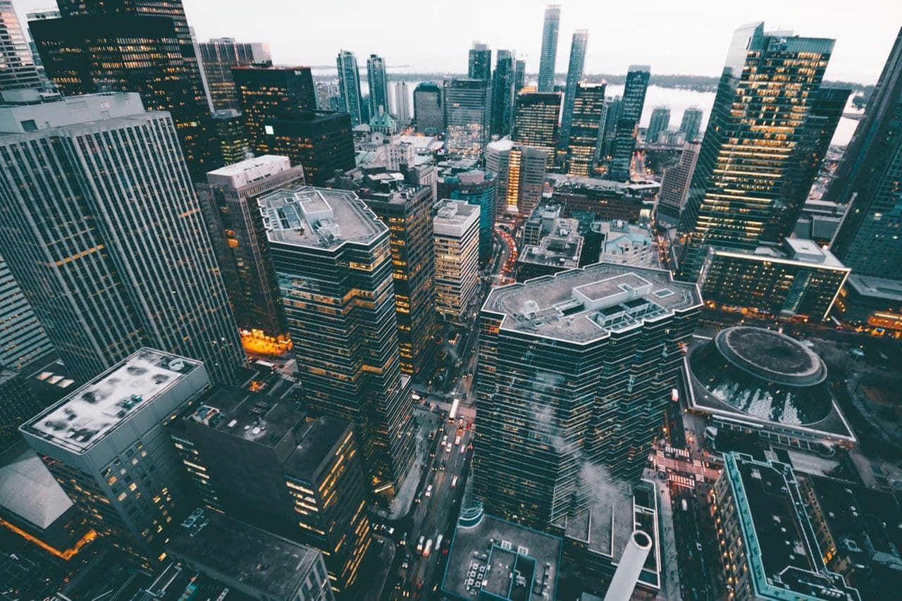 Aerial view of a dense city skyline with tall glass skyscrapers at dusk.