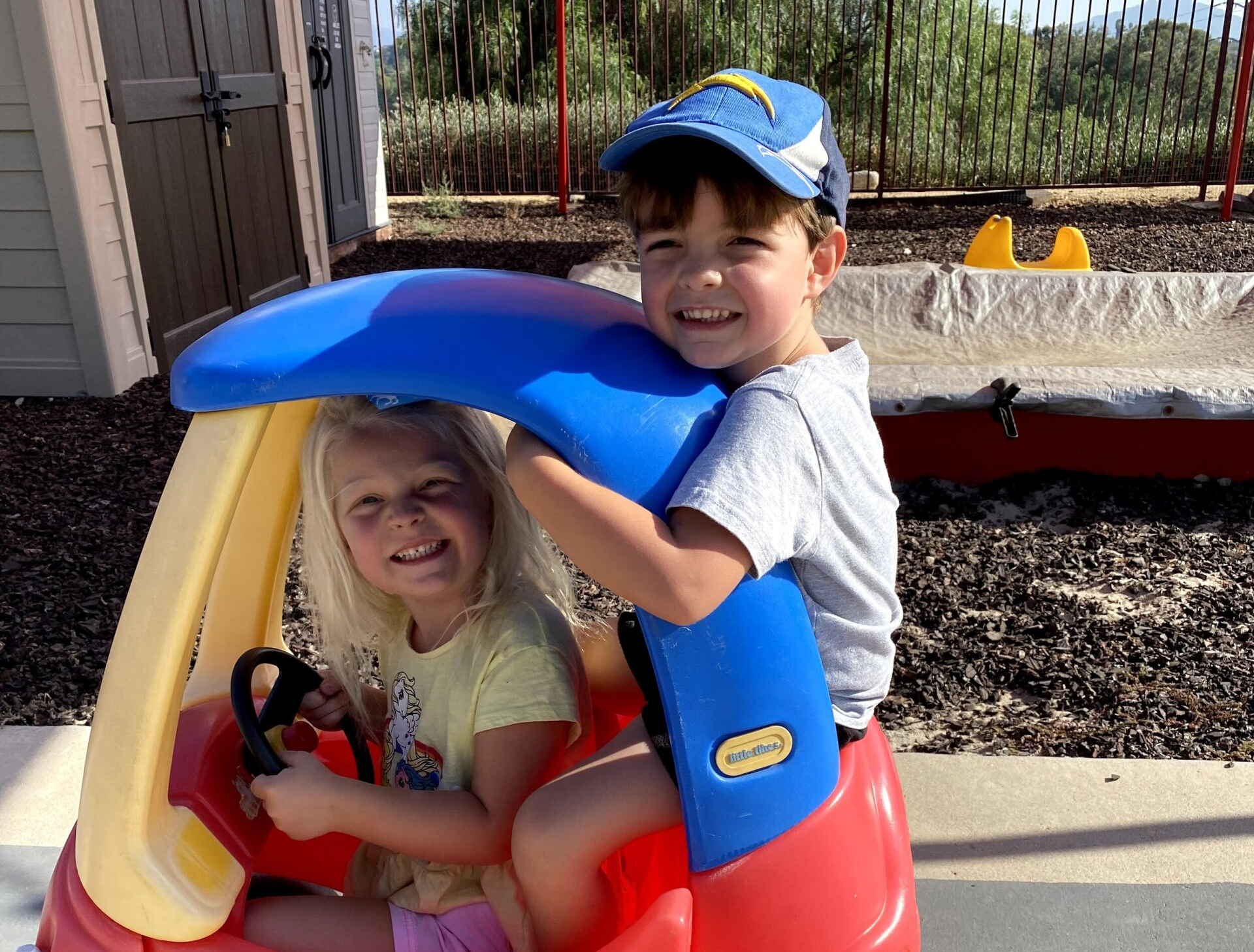 A boy and a girl are sitting in a toy car