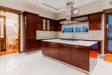 Modern kitchen with dark wood cabinets, white countertops, and a central island under recessed lighting