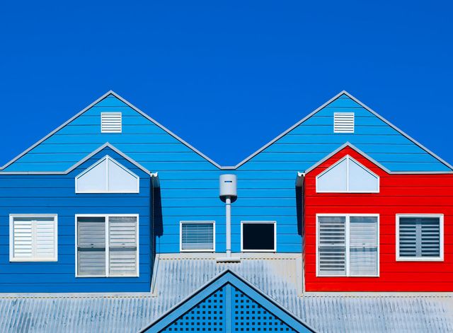 Blue and red beach houses with white trim and shutters under a clear blue sky