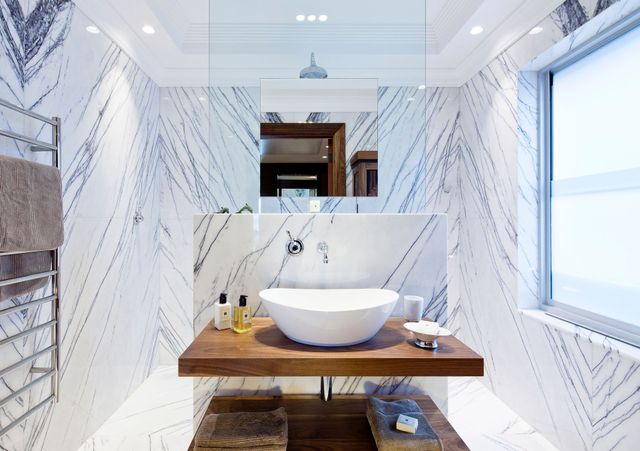 Modern bathroom with a wooden vanity, round vessel sink, patterned tile walls, and large window