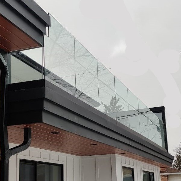 A balcony with a glass railing on the side of a house