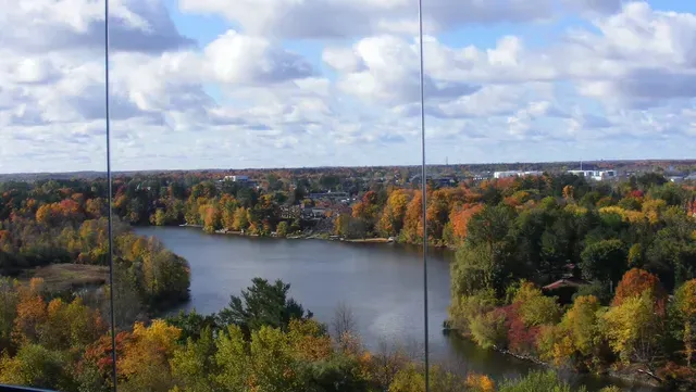 Autumn landscape with lake and colorful trees under a cloudy sky.