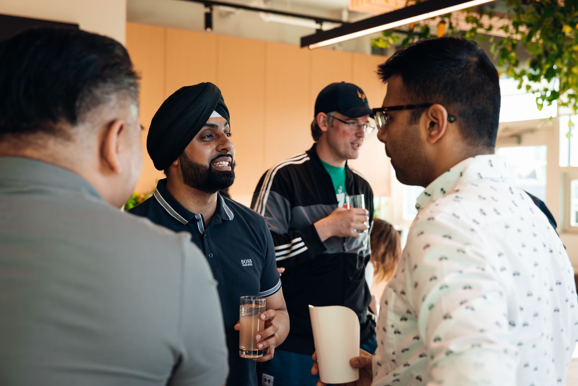 Four people chatting and holding drinks in a bright indoor lounge area