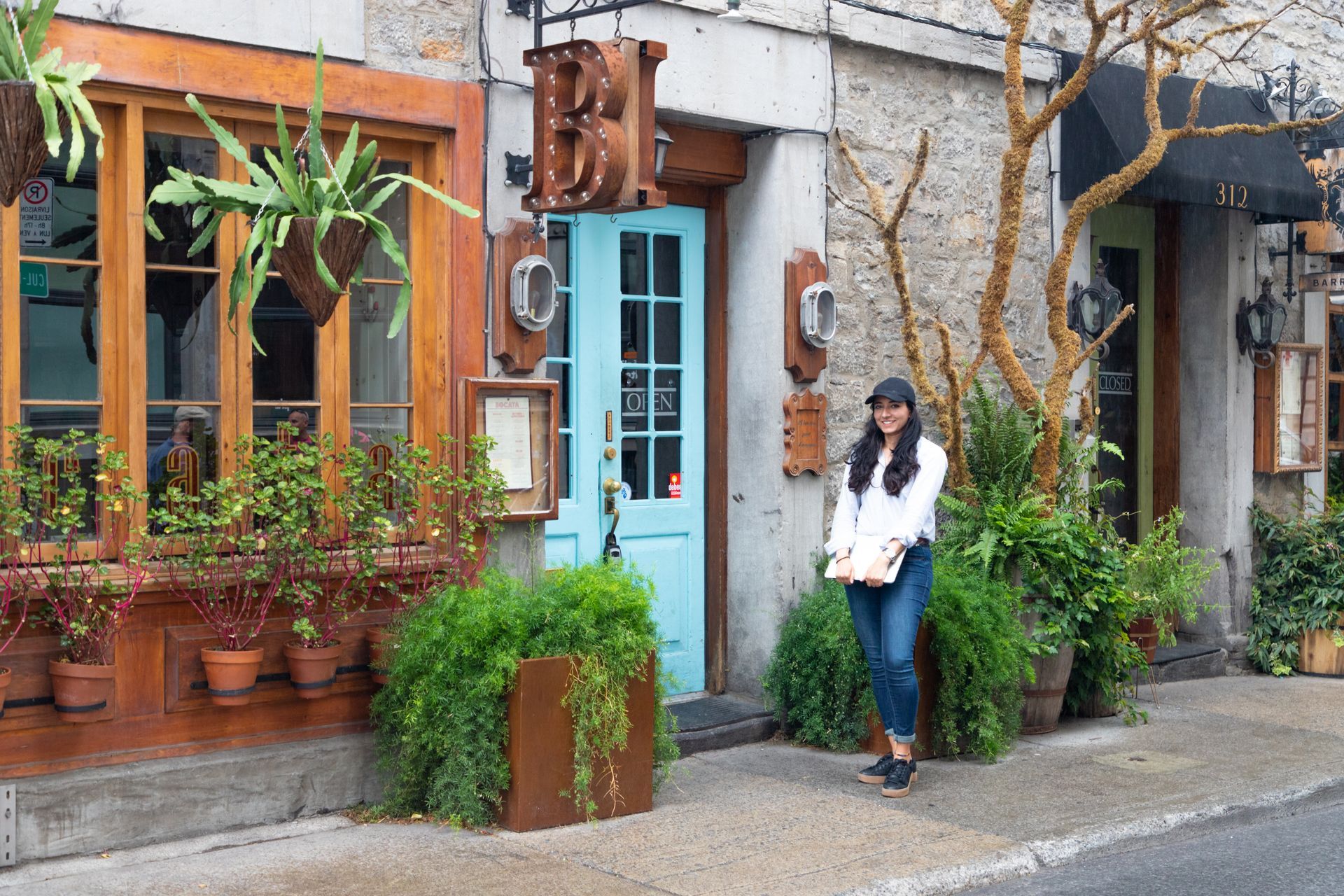 Woman standing outside a colorful storefront with potted plants and a blue door