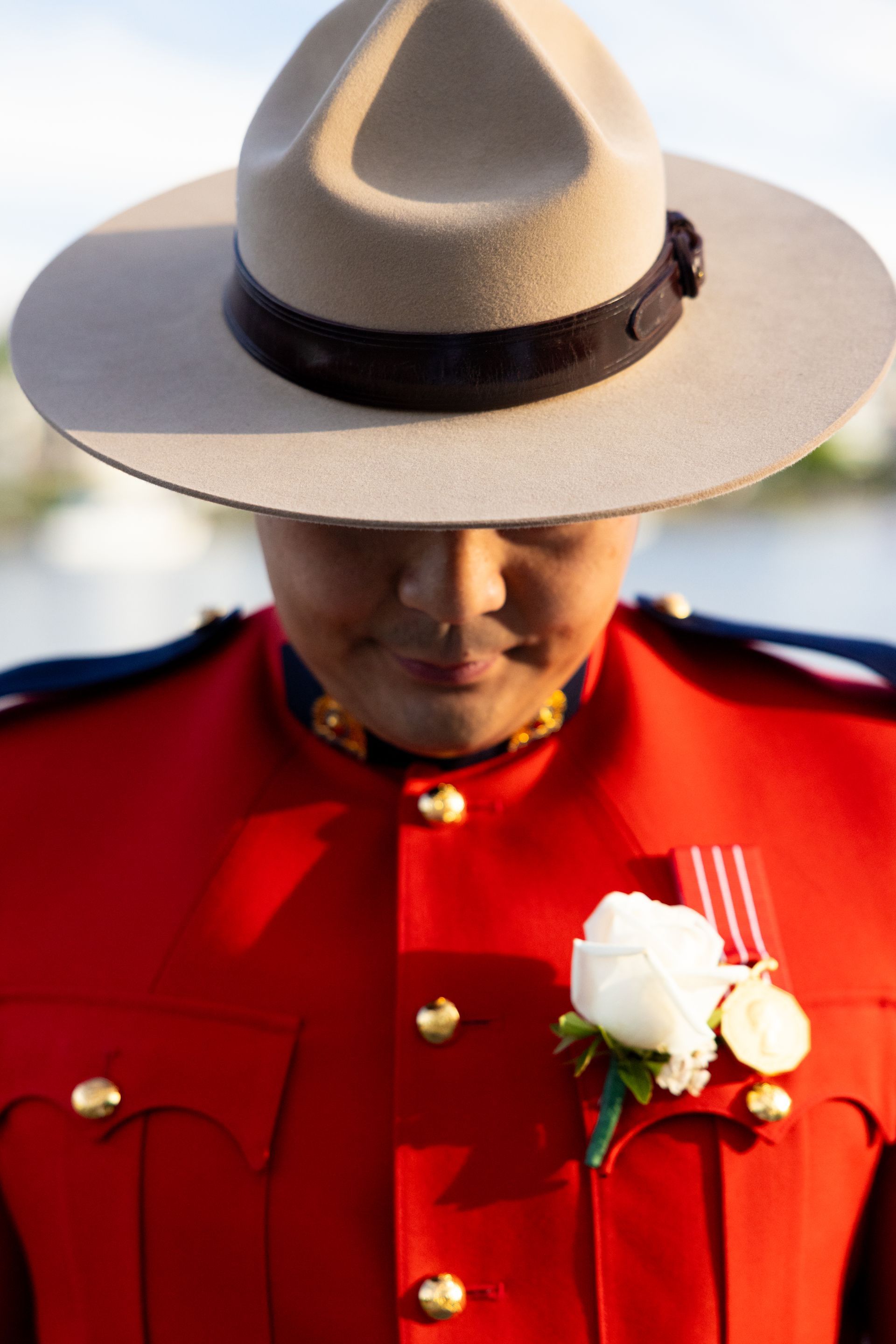 Person in a red uniform and white hat with white flowers, looking downward.