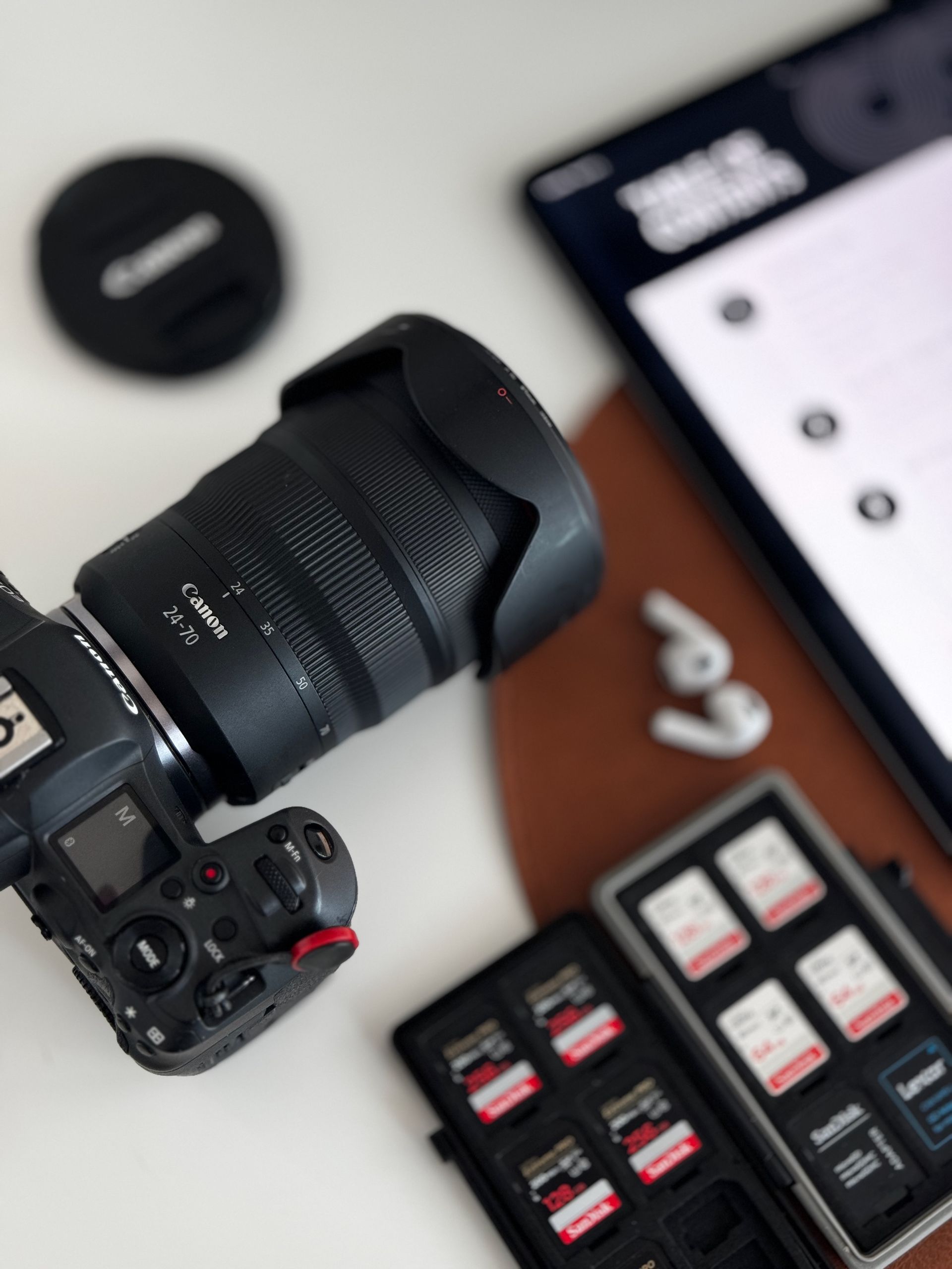 Camera with large lens beside memory cards and a smartphone on a desk