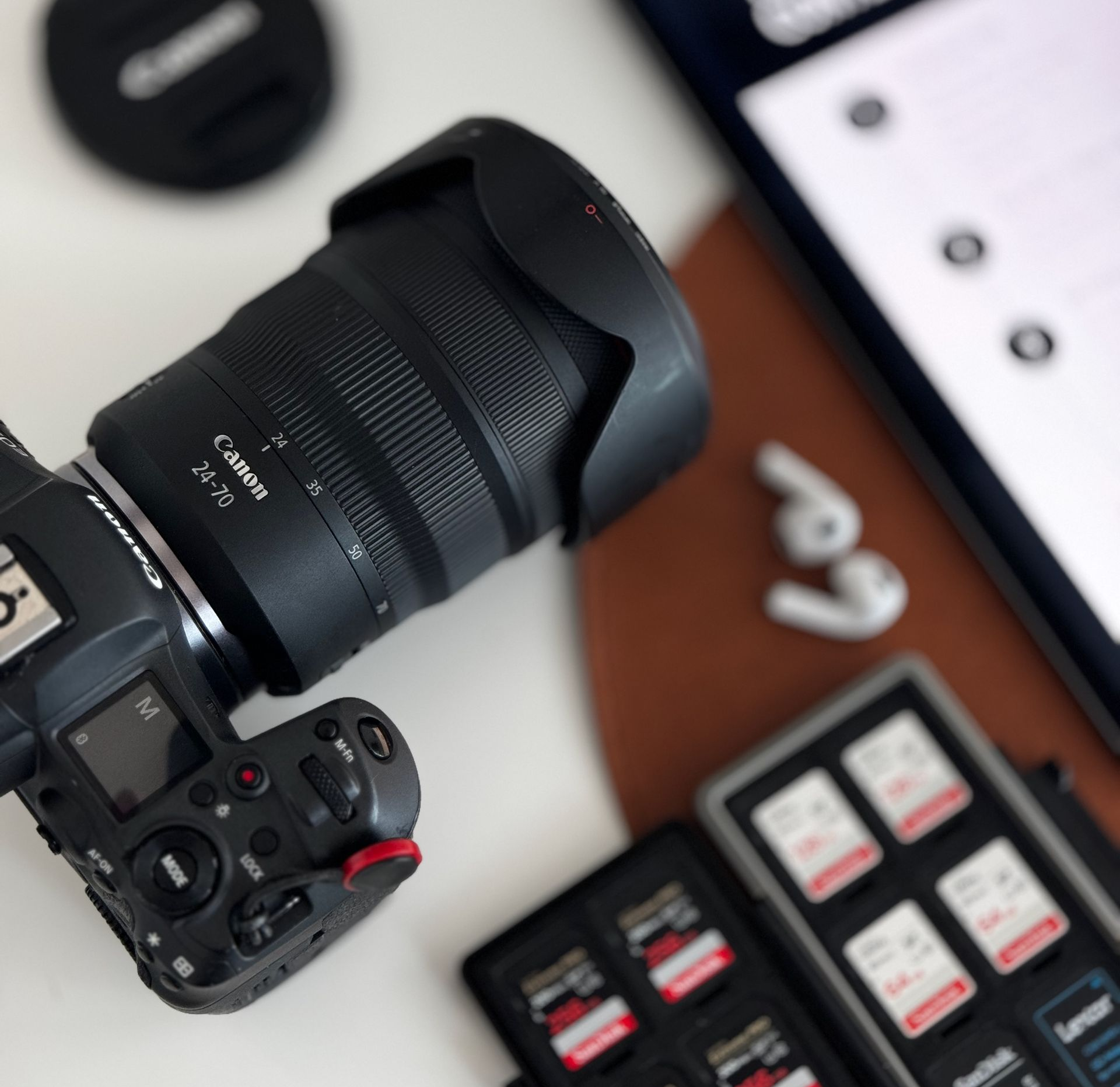 Camera with large lens on a desk beside memory cards and a phone