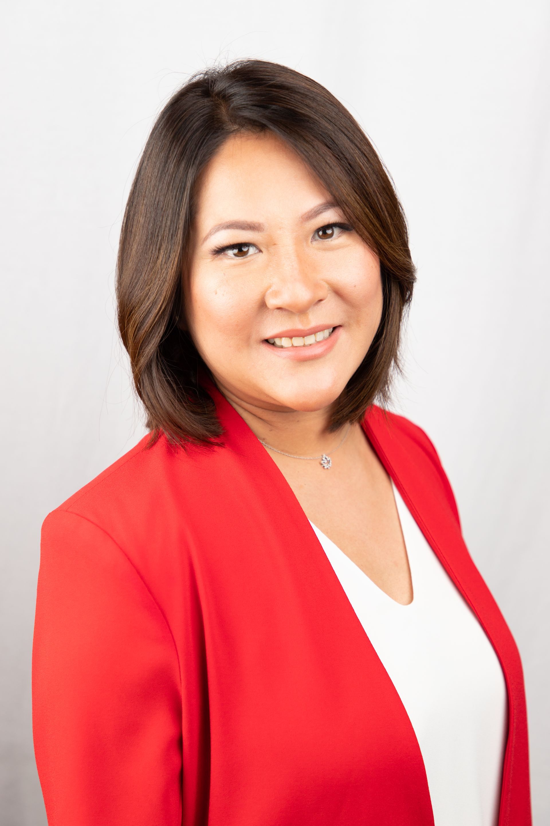 Smiling person in a red blazer and white top against a light background