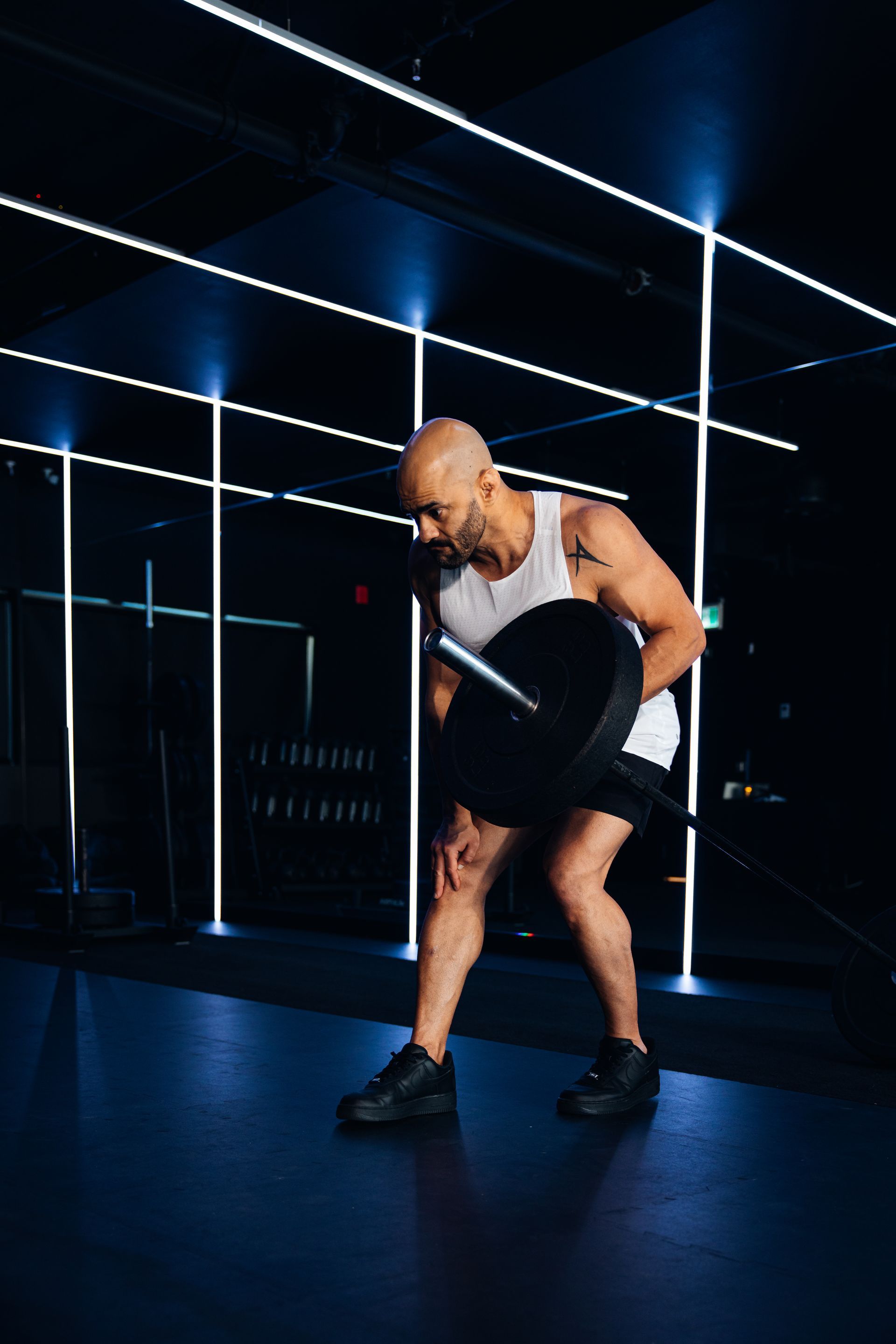Athlete lifting a barbell in a dark gym with blue neon lights