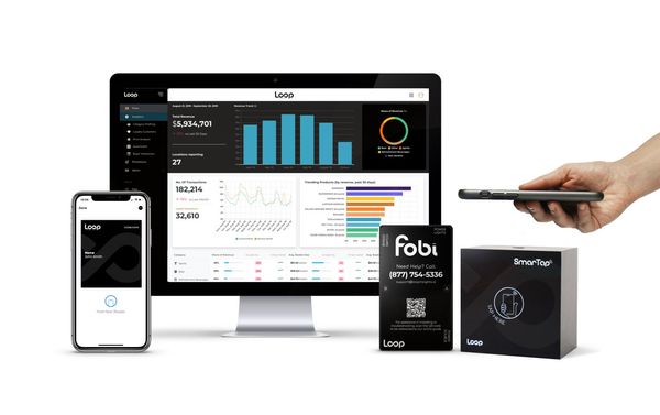 Smartphone app dashboard on a desktop monitor, with a phone, hand holding a device, and product box on white background