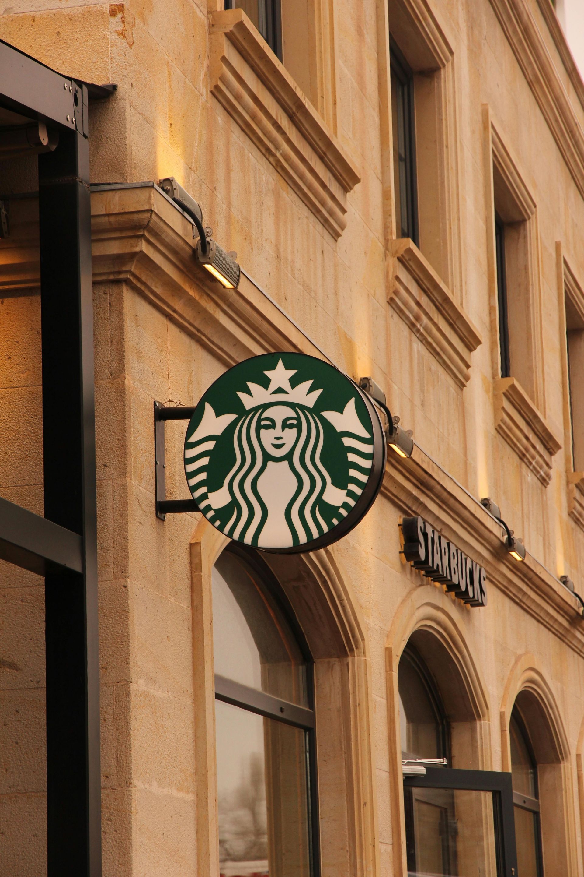 Starbucks logo on a beige storefront above arched windows in a city street