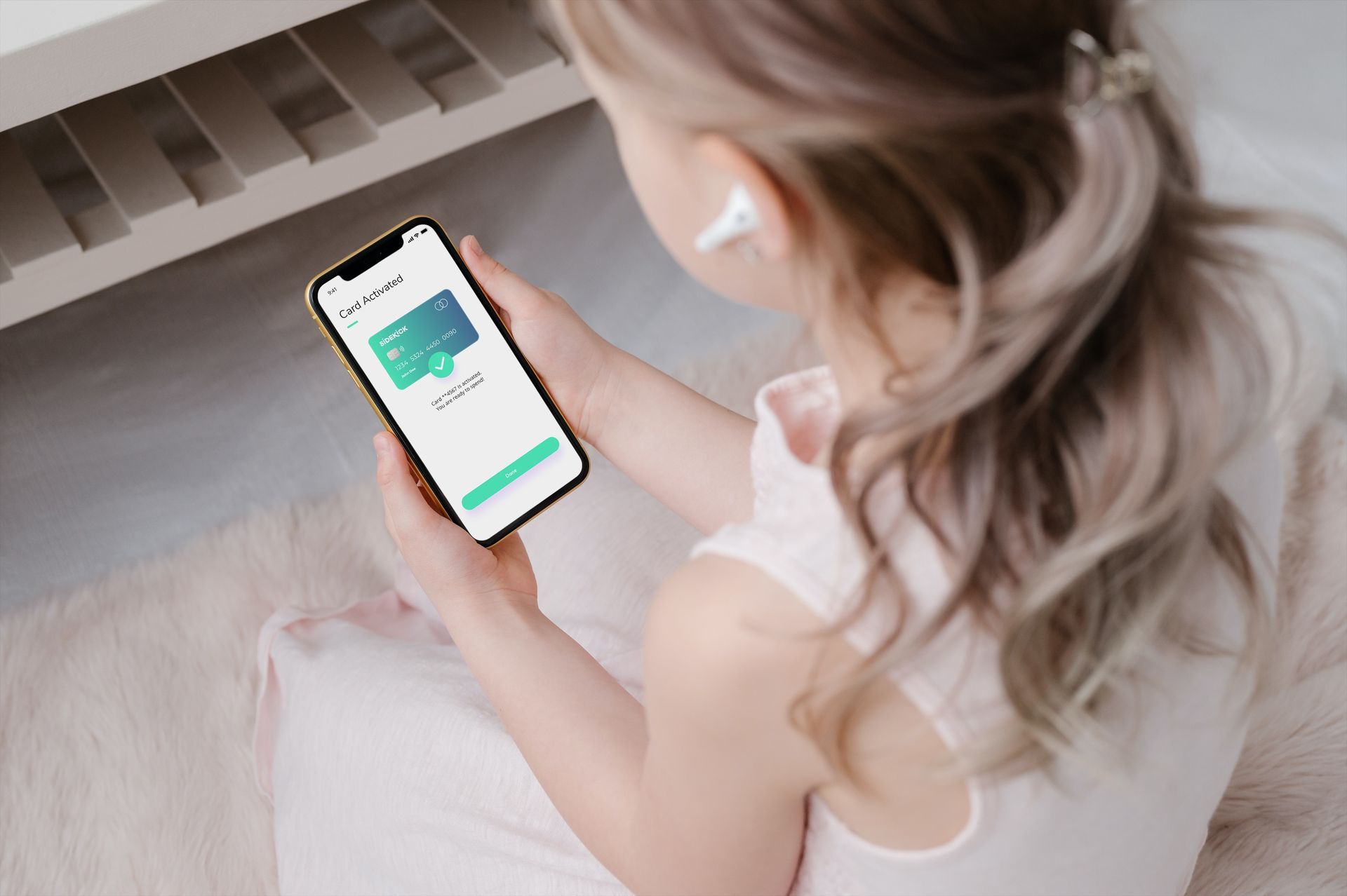 Person using a smartphone while sitting on a bed with a small green app on the screen