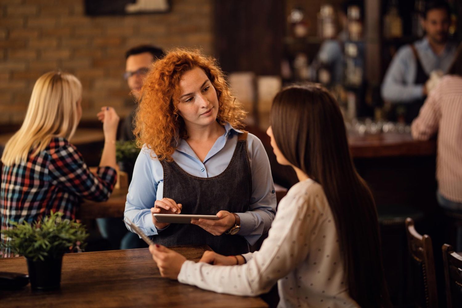 Waitress taking an order from two diners in a dimly lit restaurant