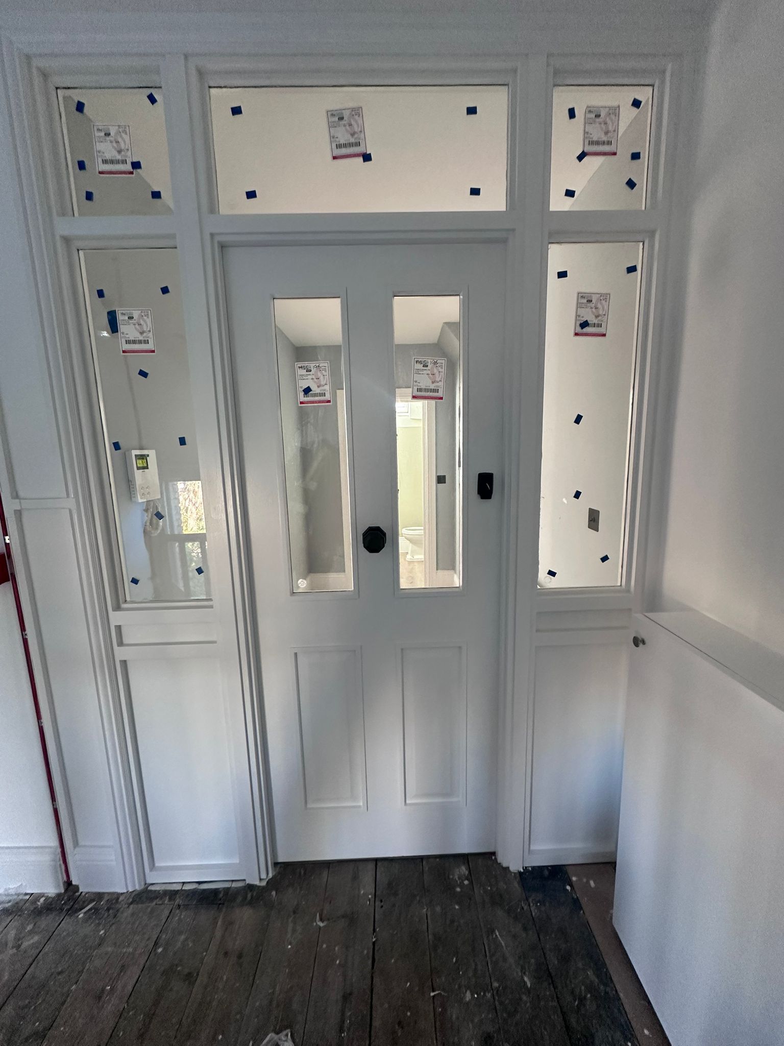 White front door with sidelights, door has glass panels.