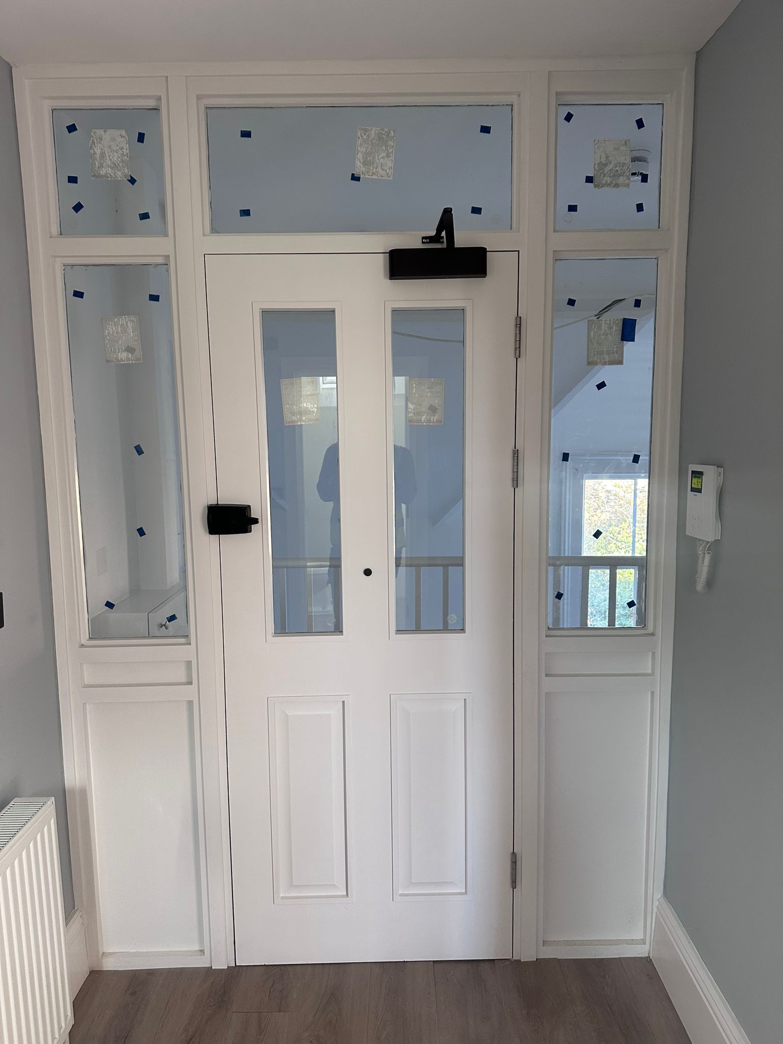 White front door with glass panels and side windows in an entryway.