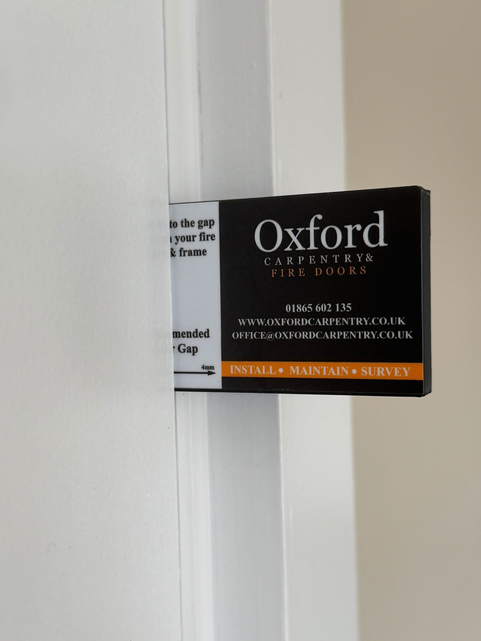 Black Oxford Safety Door device on a white door frame, with text: