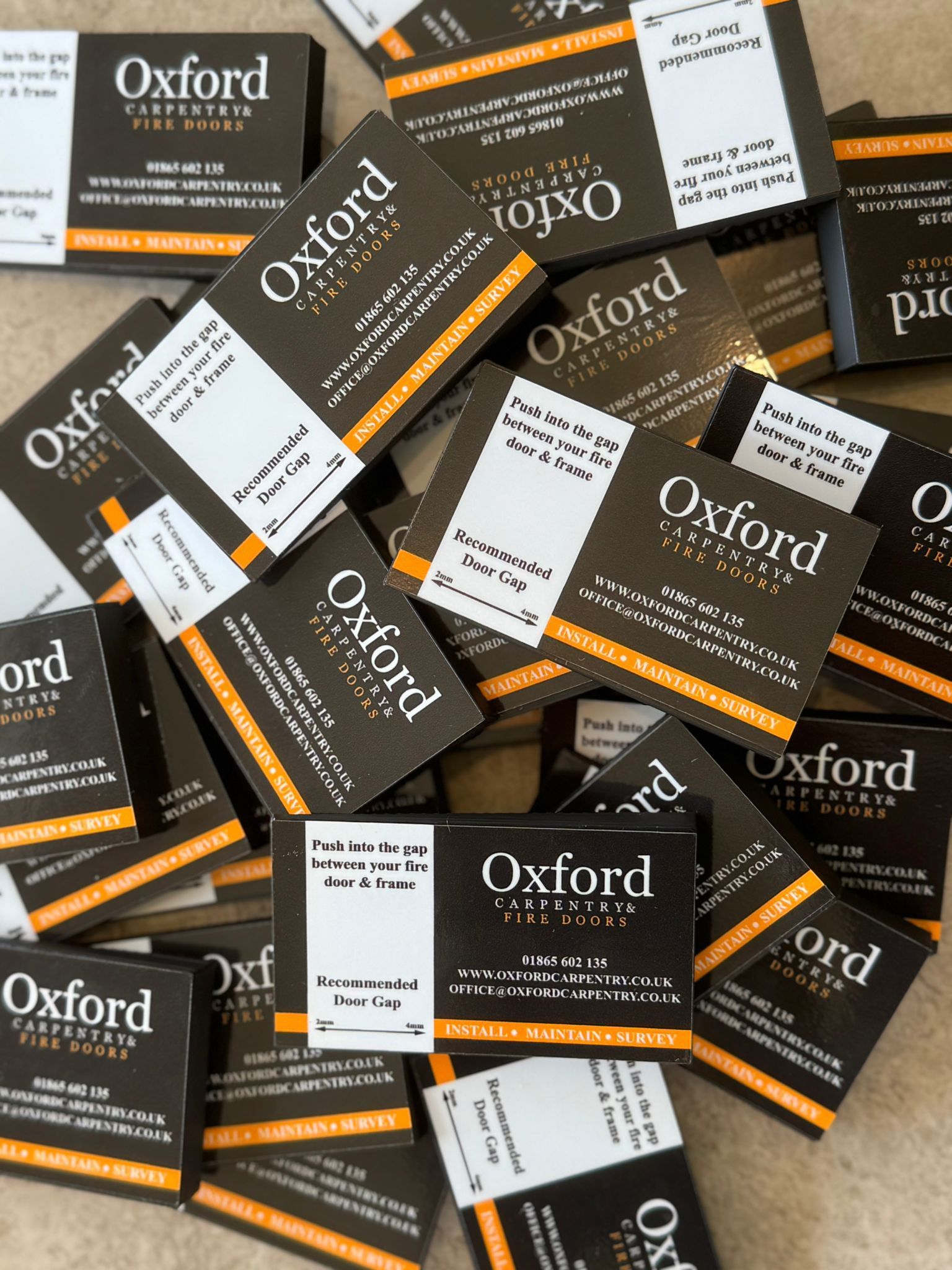 Pile of Oxford business cards, mostly dark brown with white and orange accents.